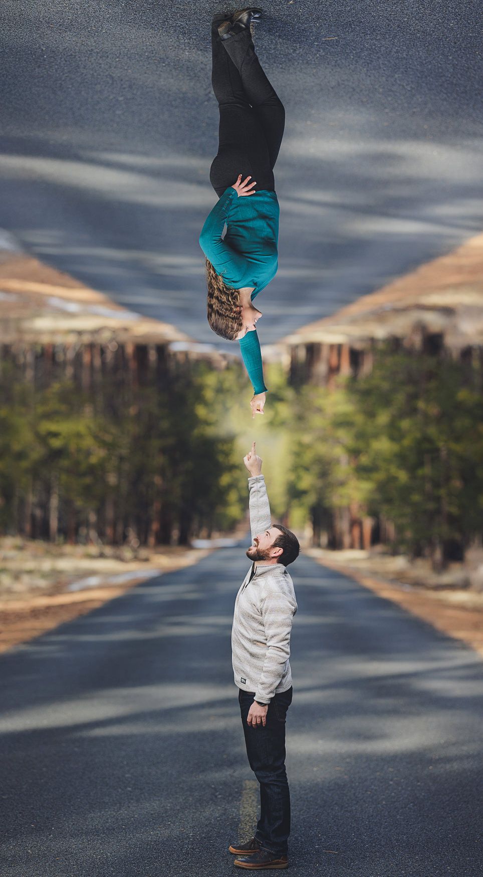 Artistic upside down portrait on a road shows creative perspective as one person appears to be holding another by the feet.