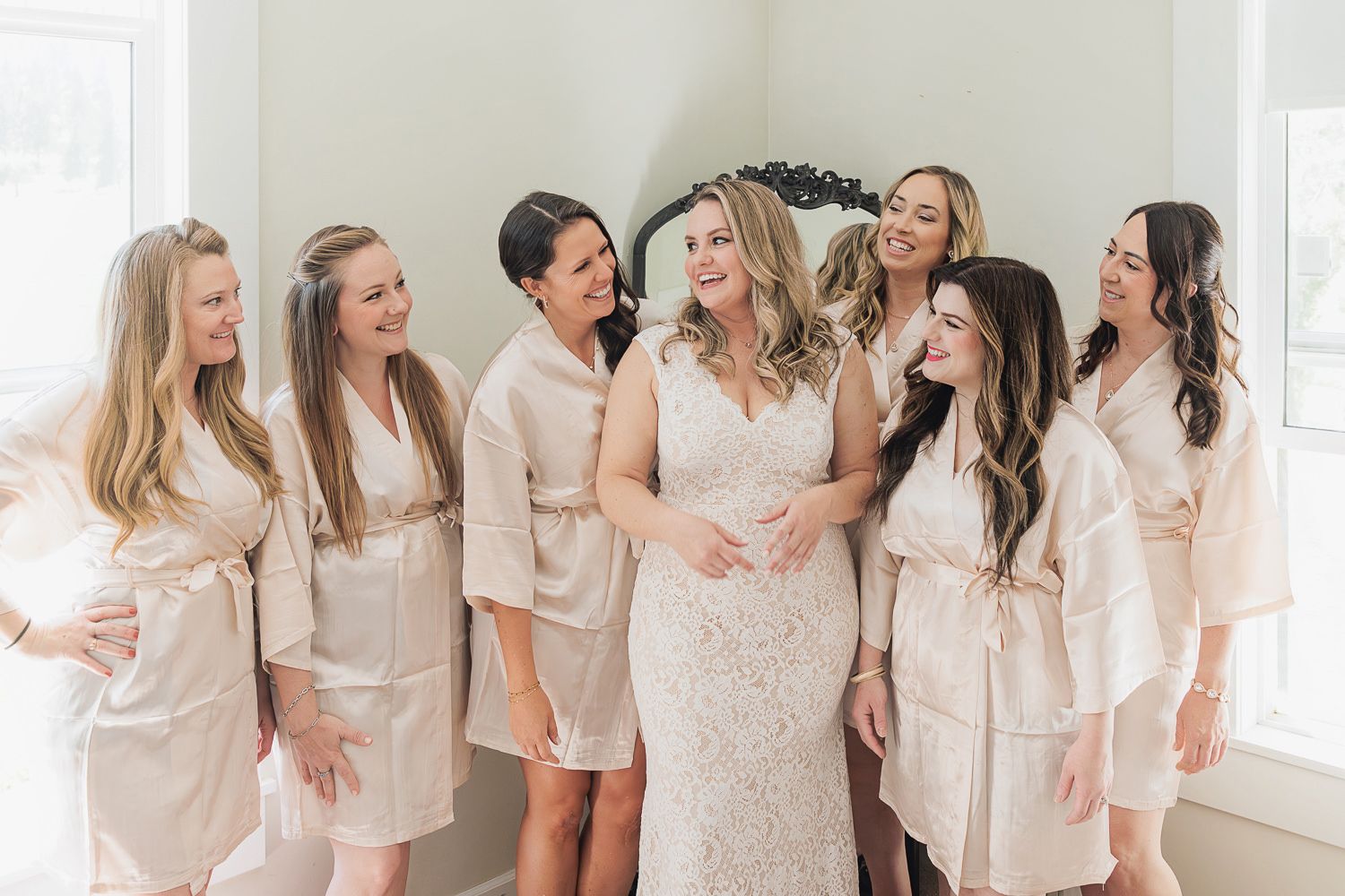 Women in white and cream dresses laugh and share joyful moments at a social gathering.