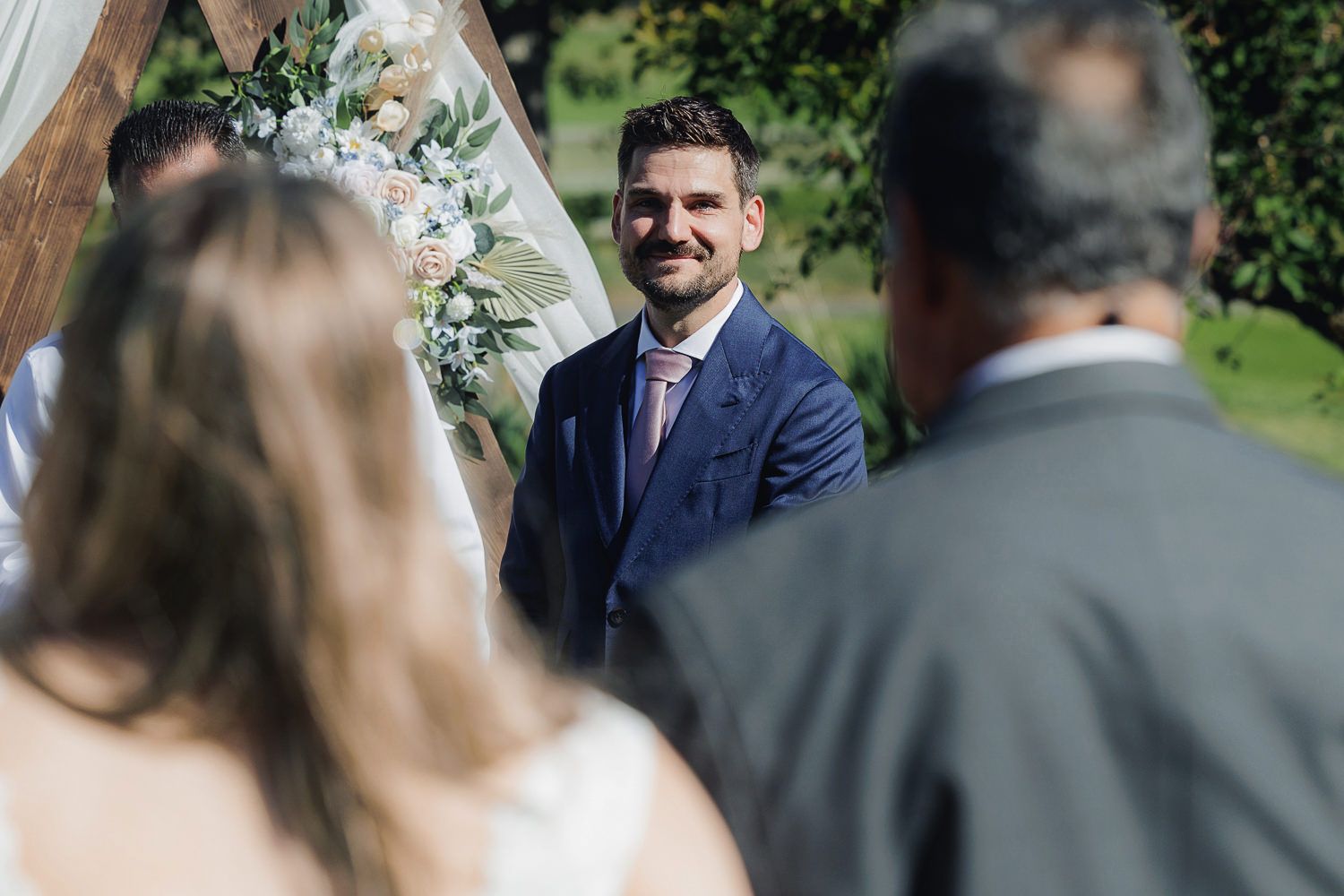 A joyful moment during an outdoor garden wedding ceremony with greenery and white floral decorations.