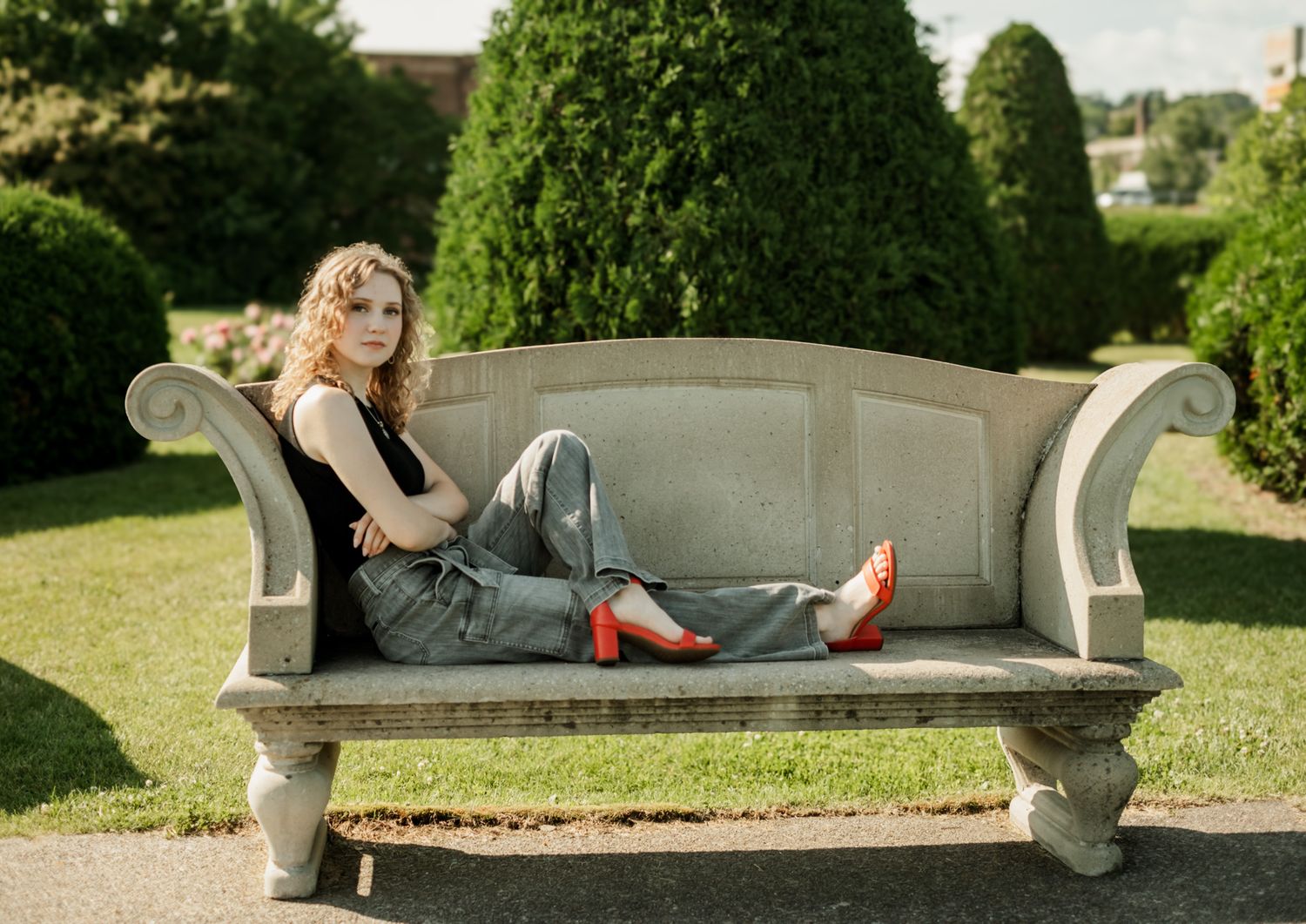 Various relaxed poses on an ornate stone bench in a manicured garden setting.