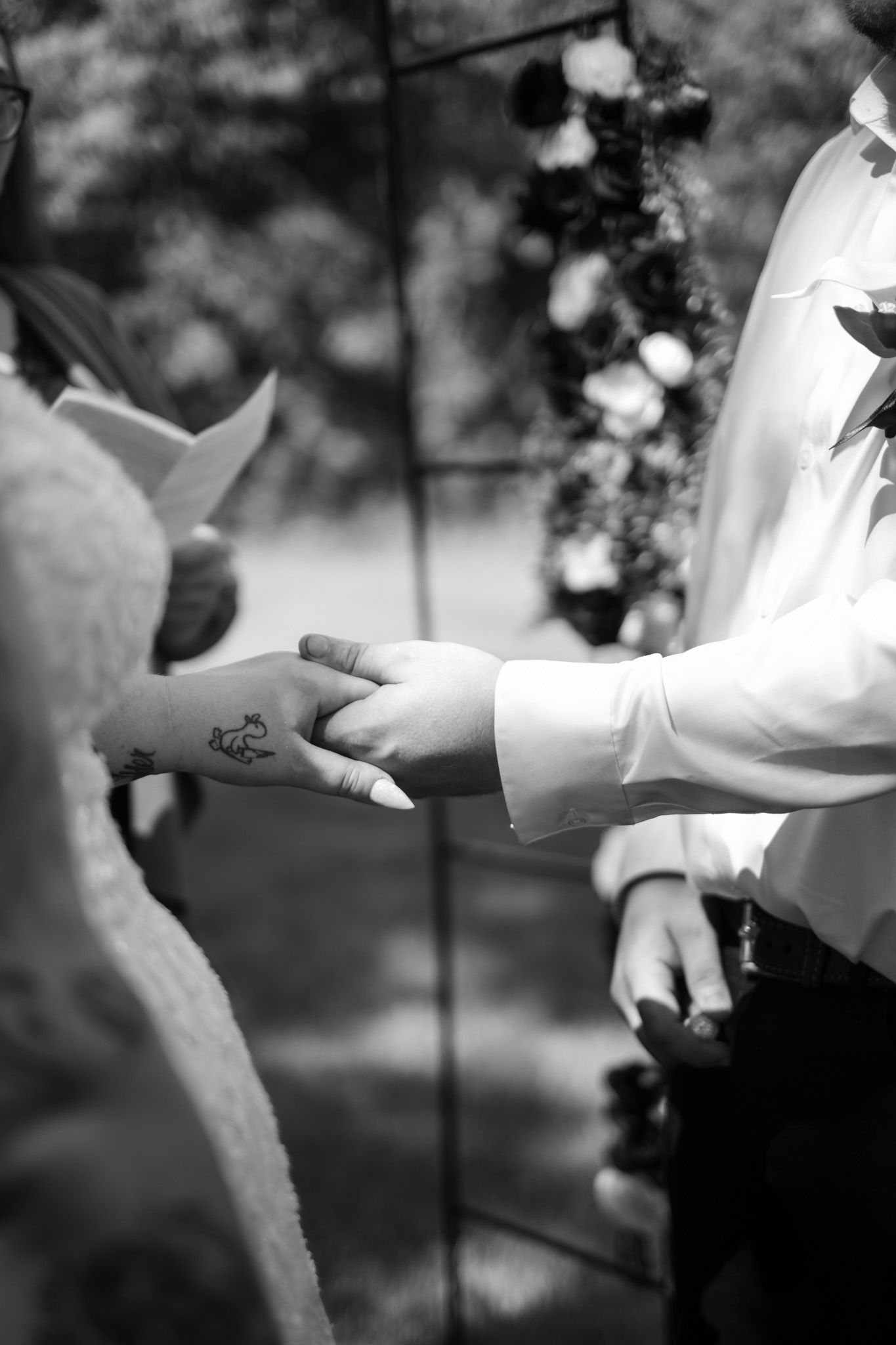 Close-up black and white shots of hands exchanging rings during a wedding ceremony.
