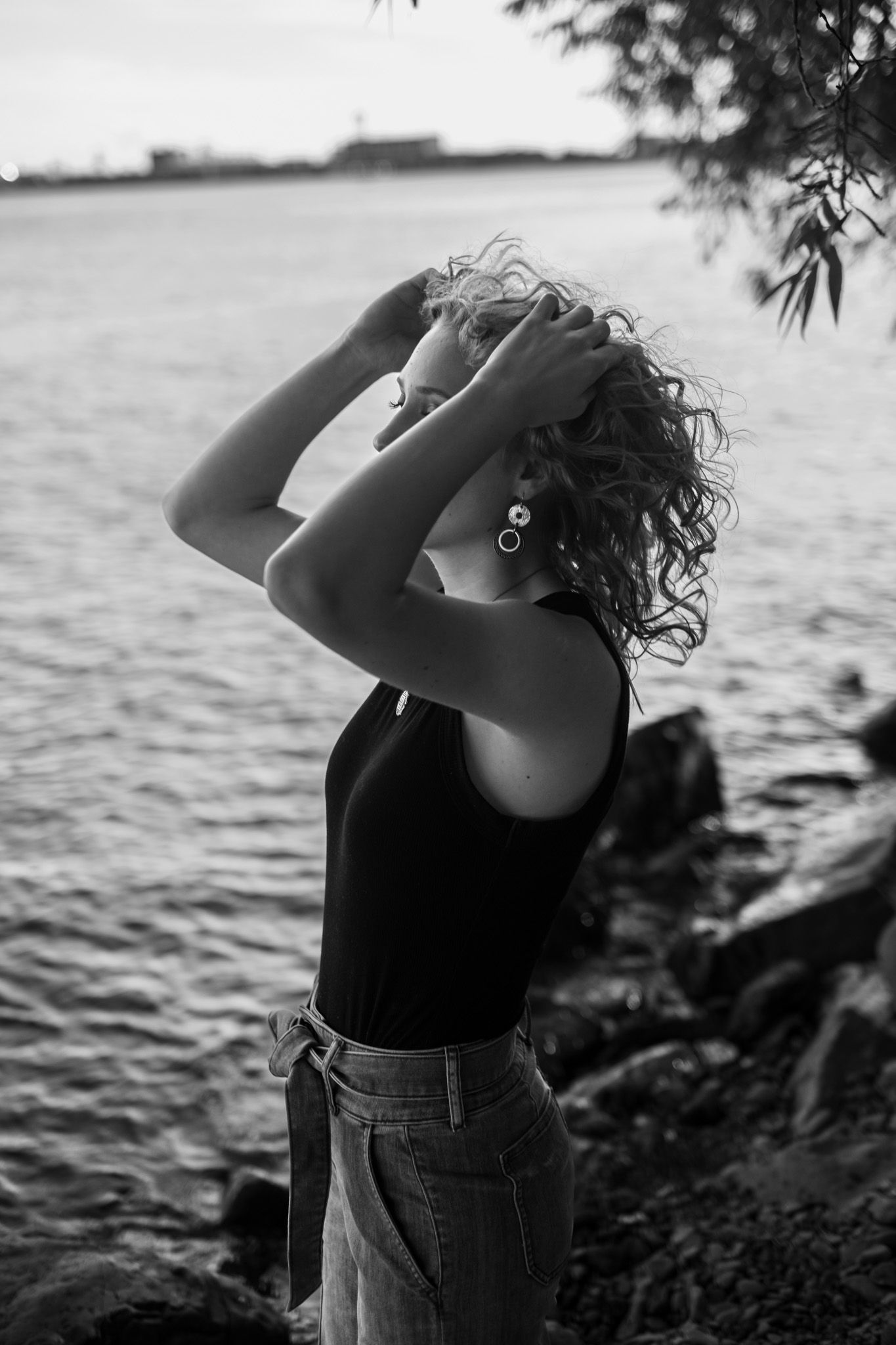 A black and white photo sequence shows a person in denim looking up at the sky near a serene waterfront.