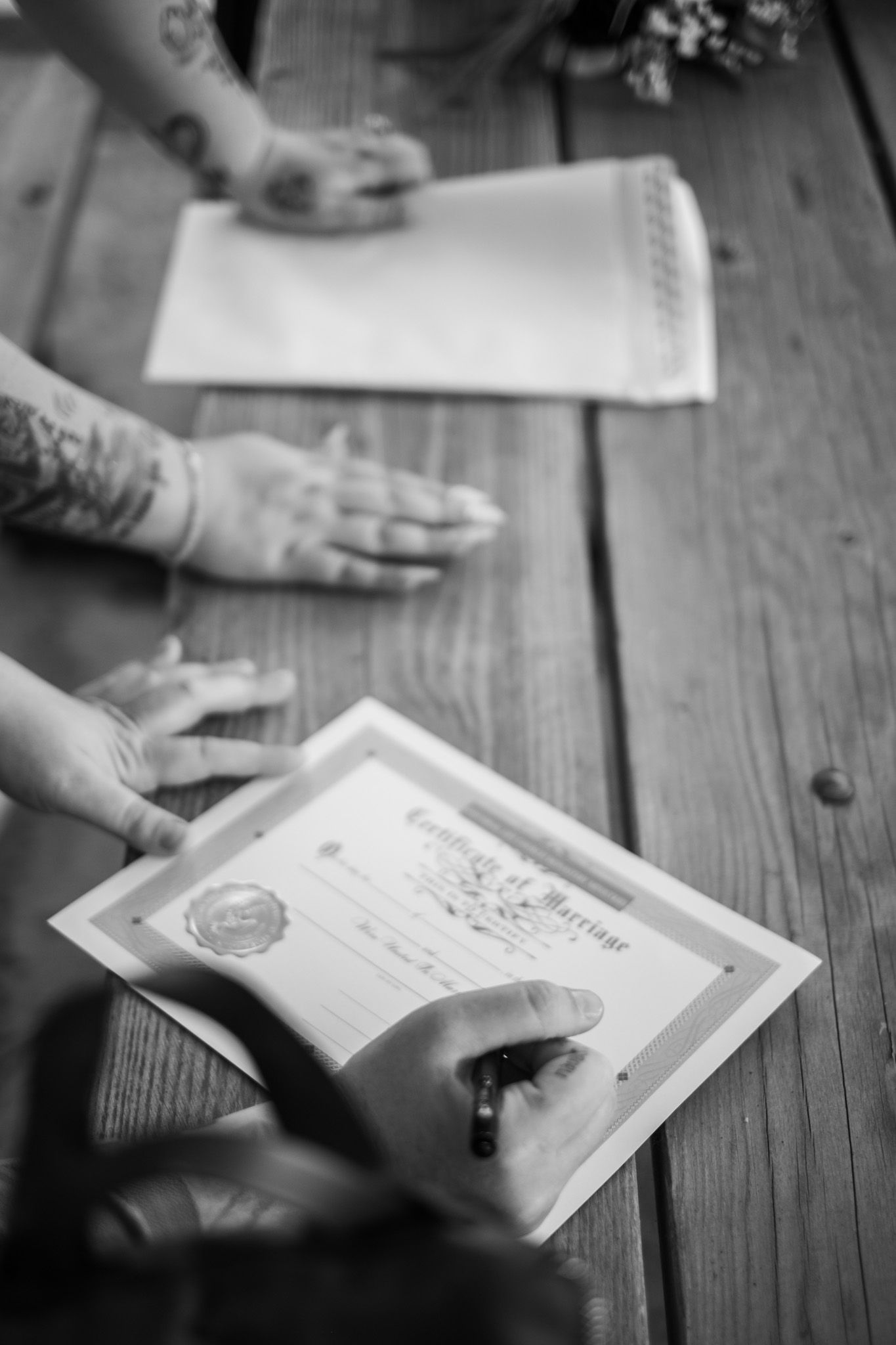 Several black and white images of hands turning pages of books laid on a rustic wooden table.