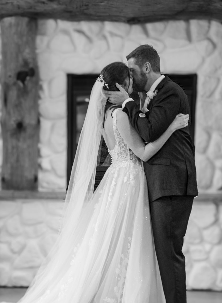Classic black and white wedding portrait against textured stone wall.