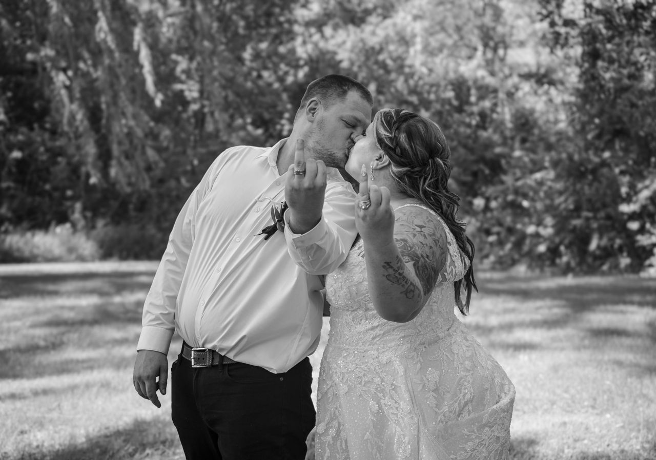 A romantic black and white portrait of a couple sharing an intimate moment in a sunlit outdoor garden setting.