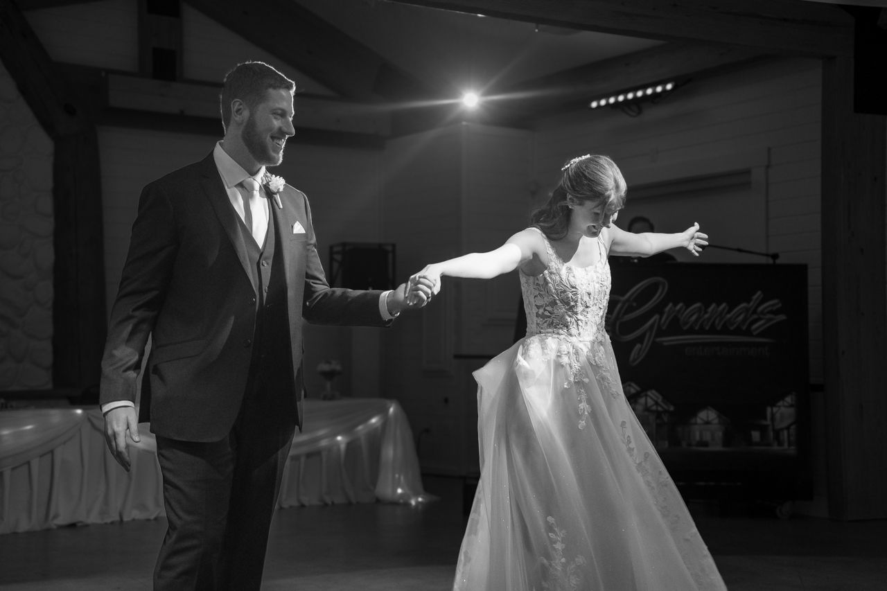 Black and white photo of a couple's first dance in an elegant reception venue.