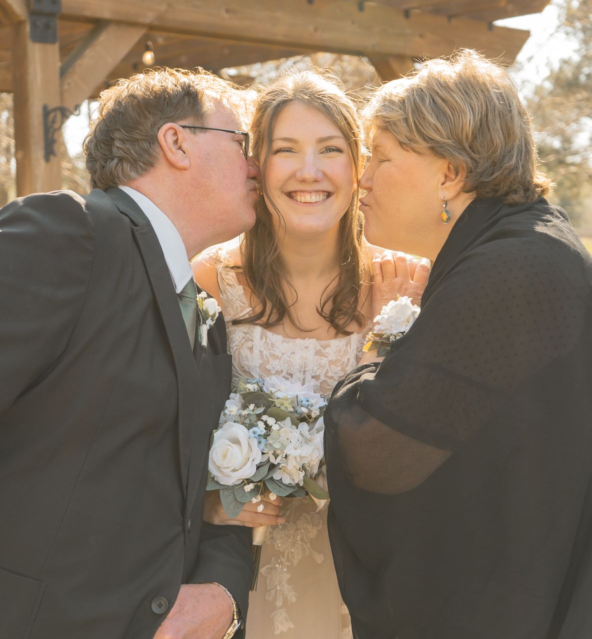 A warm sunlit moment between loved ones sharing affection while holding a white floral bouquet.
