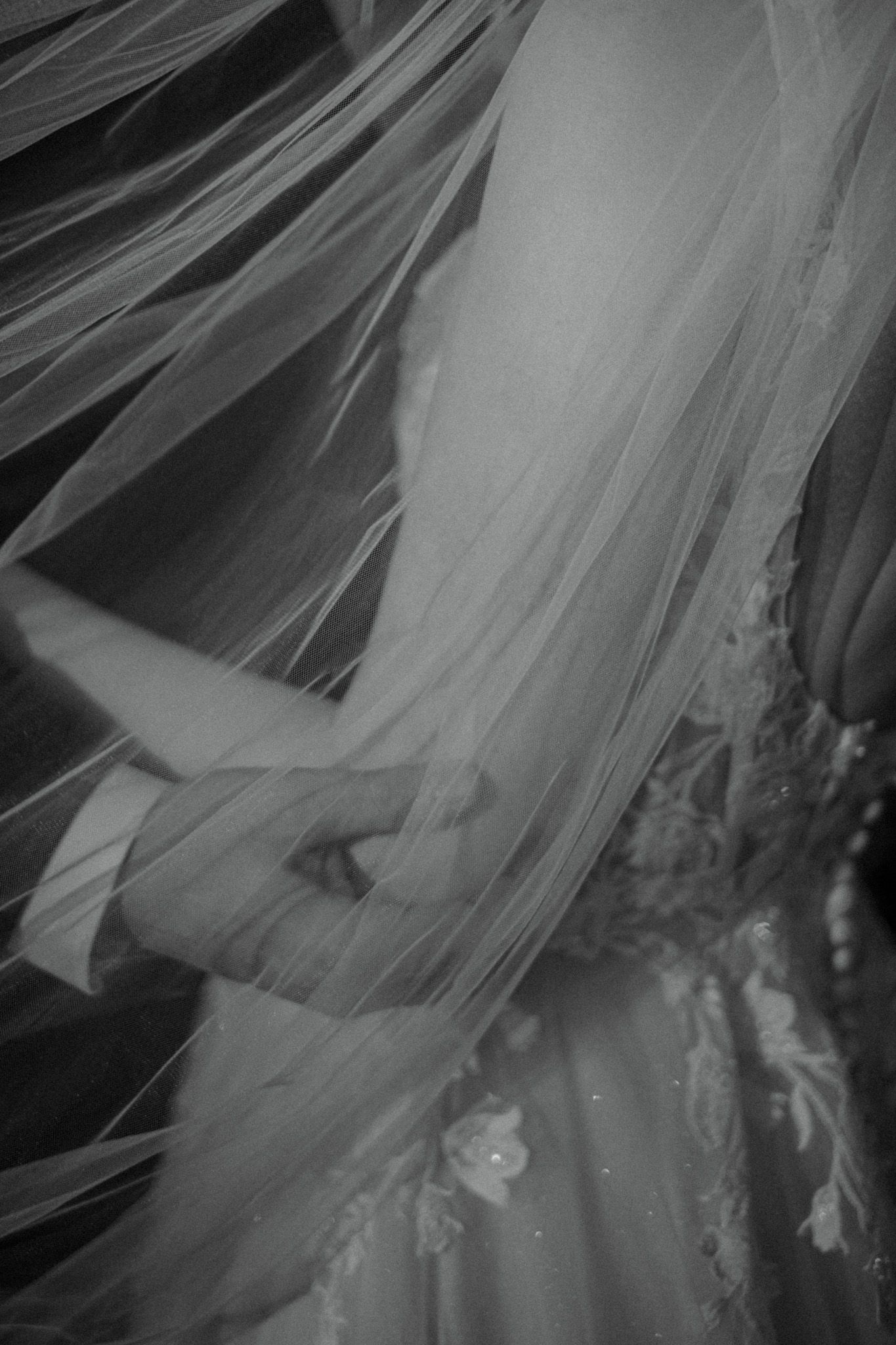 Close-up artistic black and white detail of flowing wedding veil fabric and lace.