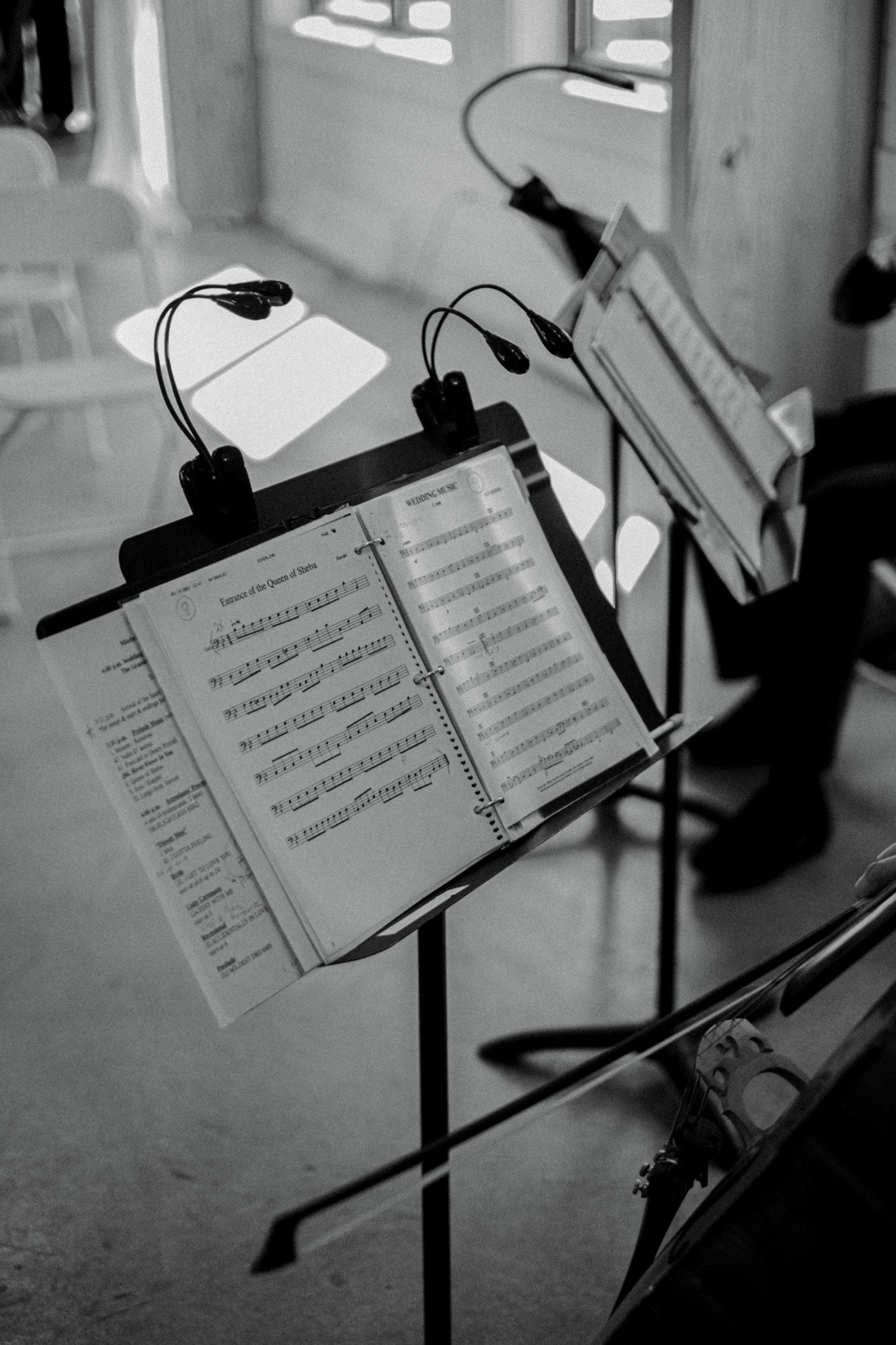 Sheet music on music stands with clip-on lights in a black and white photograph.