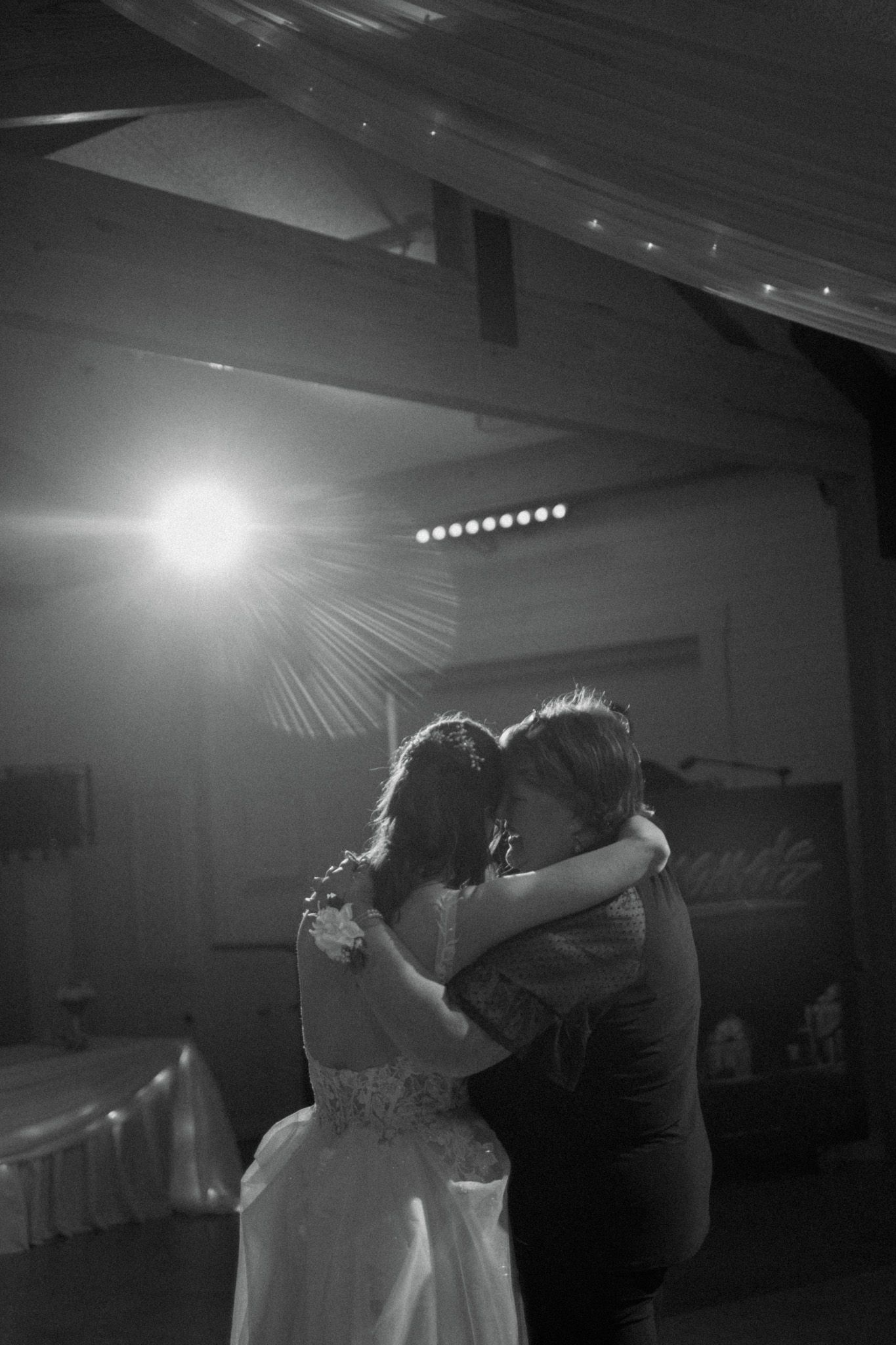 Romantic first dance silhouette at wedding reception with dramatic lighting.