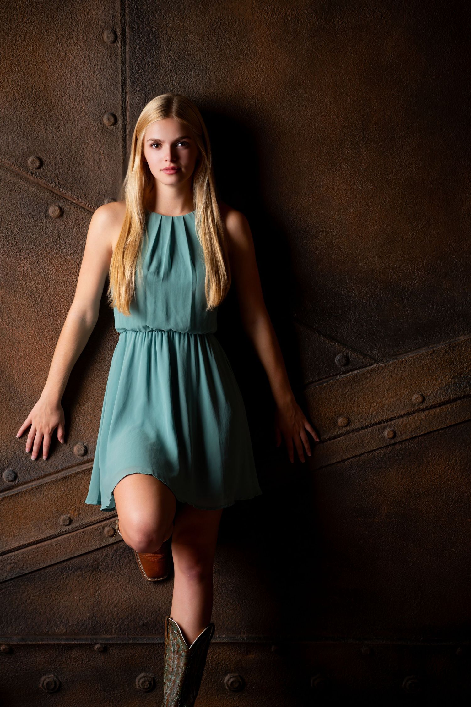 Omaha Senior Photography - Photographer in Omaha - Fashion portrait of woman in teal dress against industrial metal background.