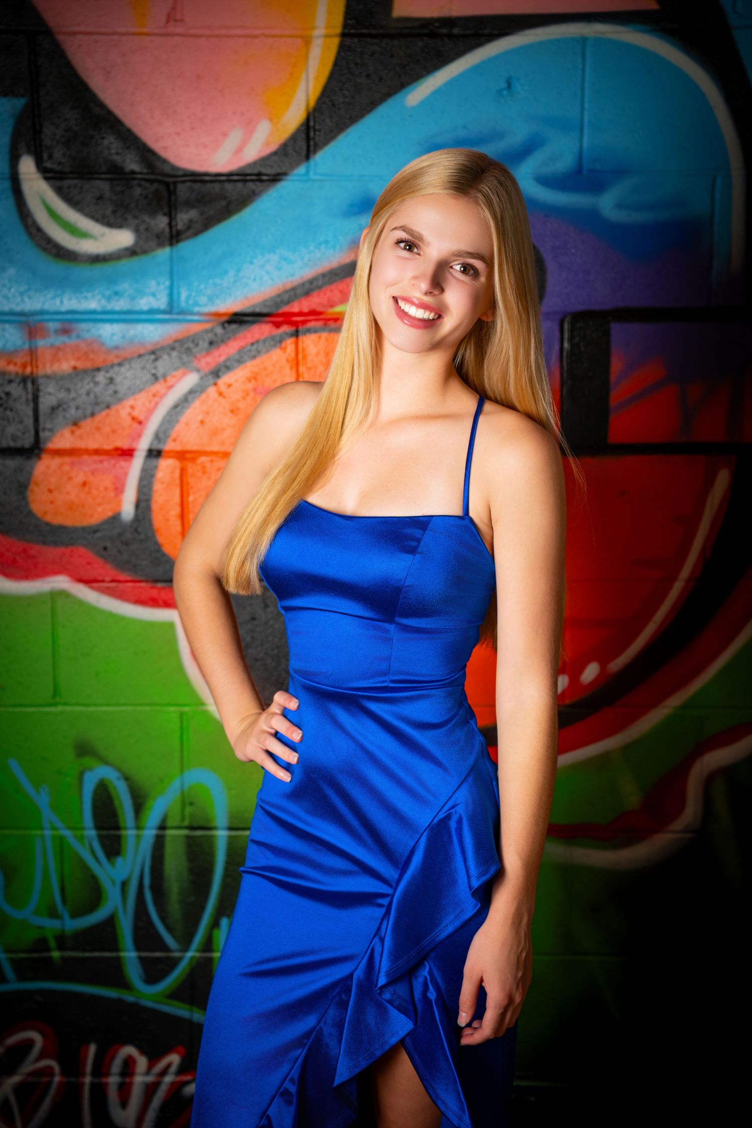 Omaha Senior Photography - Photographer in Omaha - Fashion photo in front of colorful graffiti wall wearing elegant royal blue satin dress.