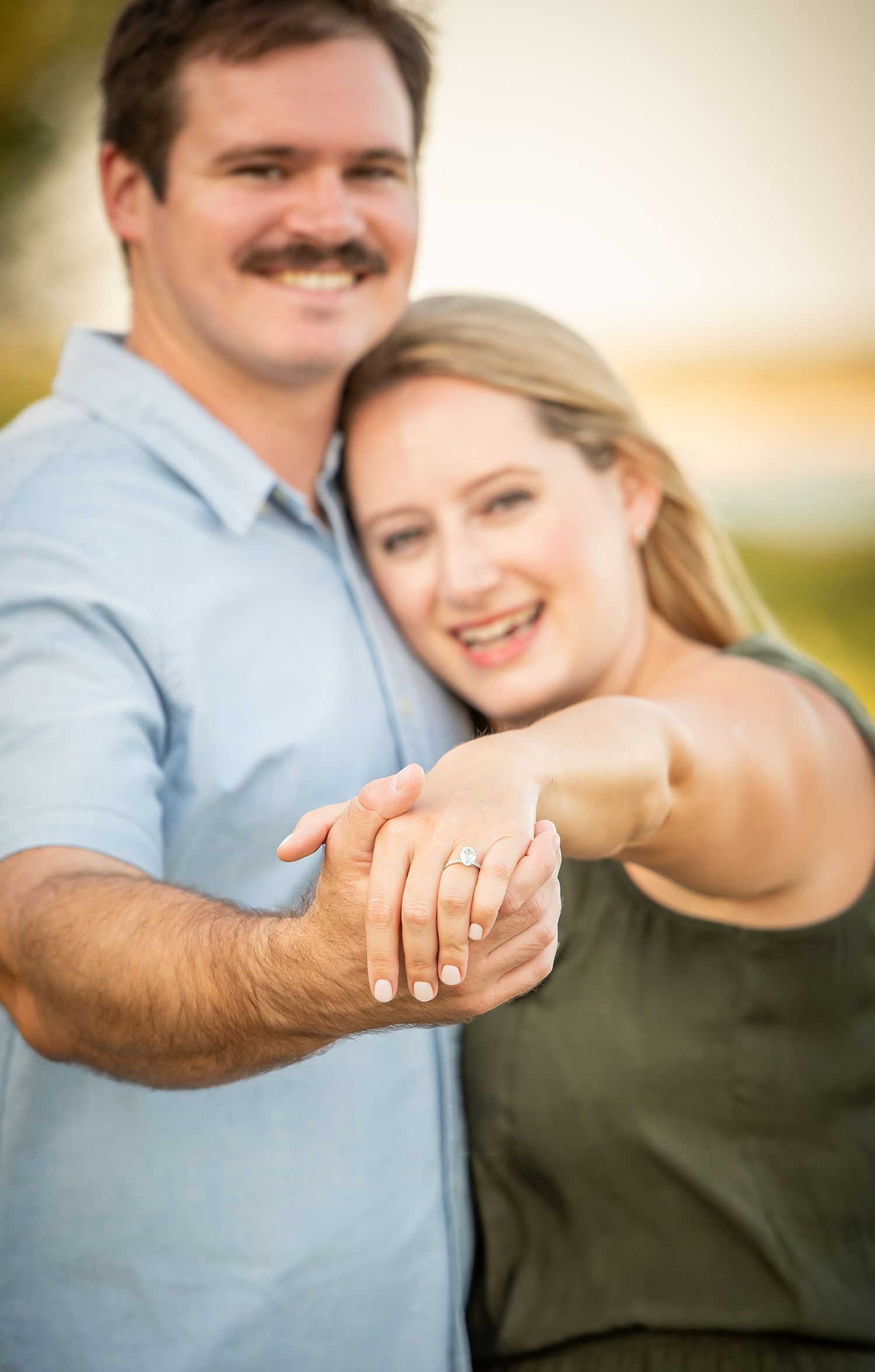 Chalco Lake - Engagement photo showing a close up of a couple's hands with a sparkly ring on display against a warm sunset background.