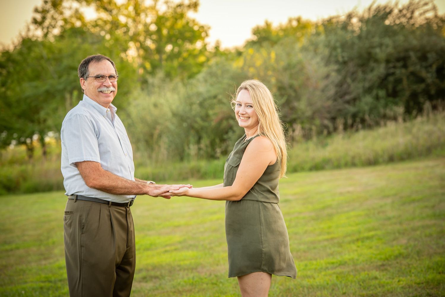 Chalco Lake Family Photography - A father and daughter holding hands in a grassy field during golden hour sunset.
