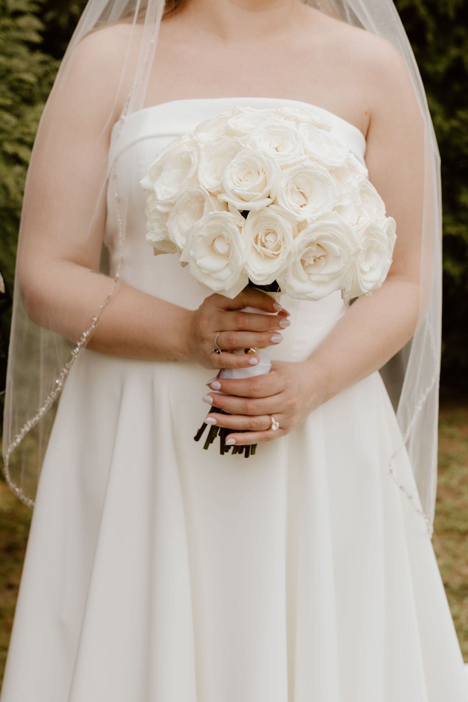 Elegant white rose bridal bouquet with flowing veil detail.