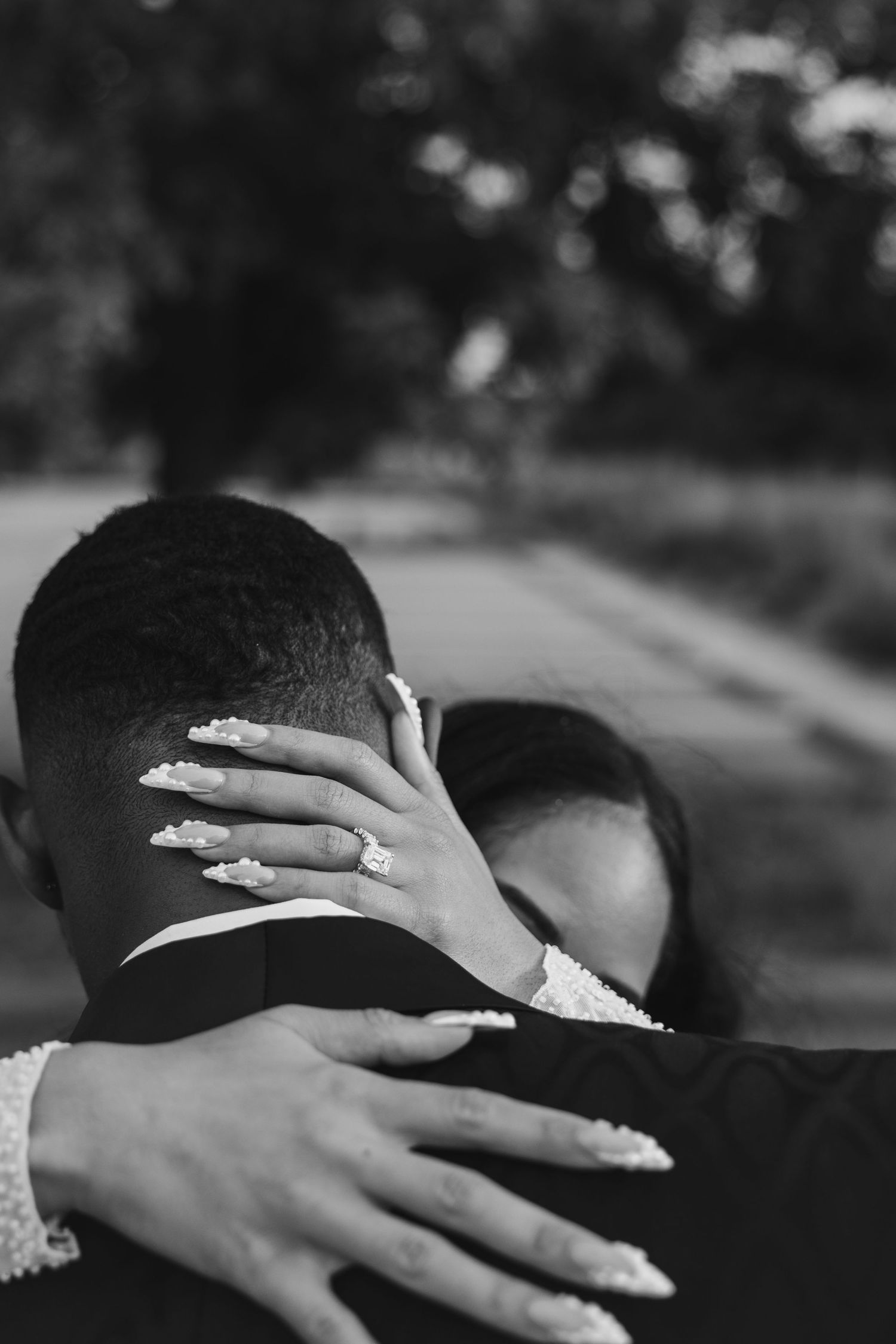 Close-up shot of hands with wedding rings embracing in a romantic black and white photograph.