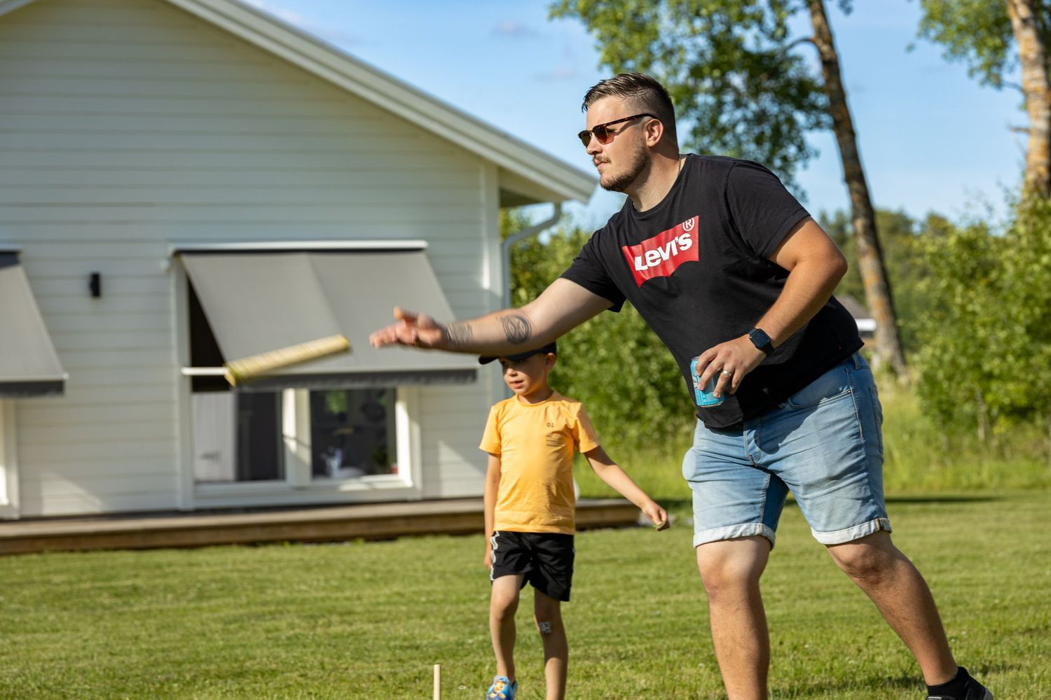 Människor som spelar kubb på en bakgård en solig sommardag.