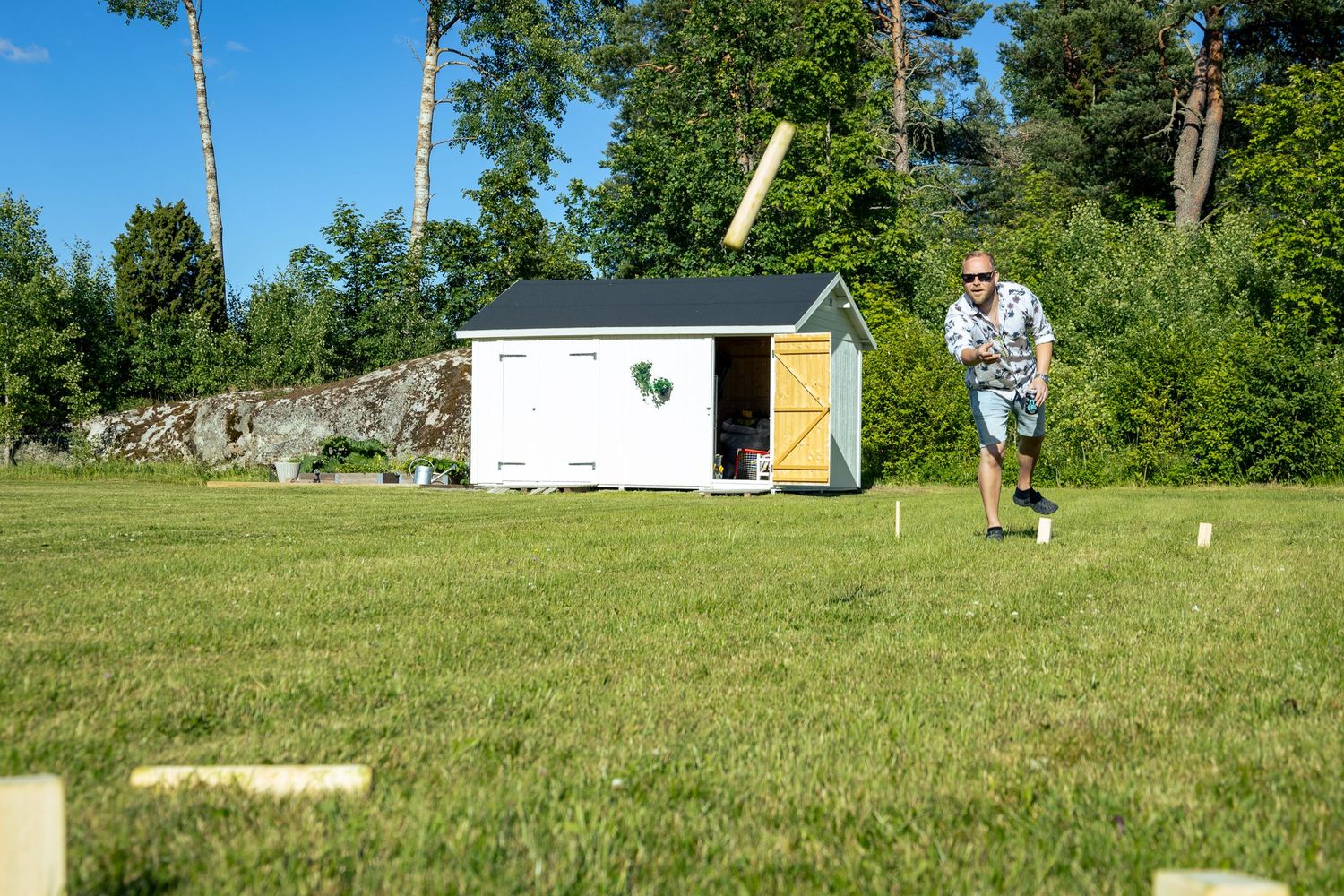 En person spelar ett kubb en solig sommardag.