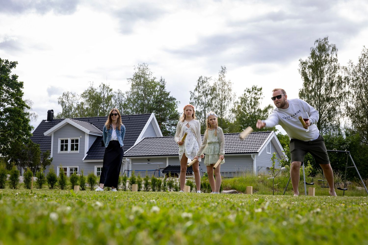 Människor som spelar kubb på gräs på gräsmattan.