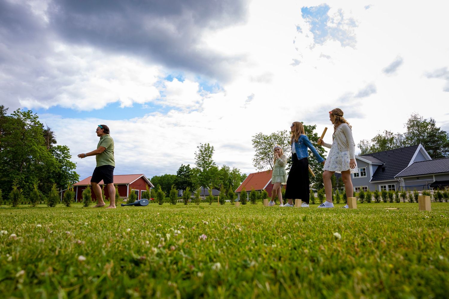 Människor som spelar kubb på gräs på gräsmattan.