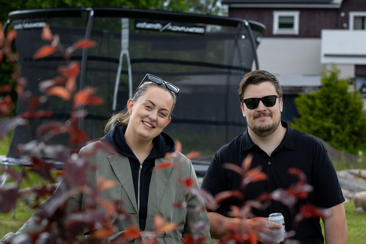 Vänner njuter av utomhussamling framför mörka buskar.