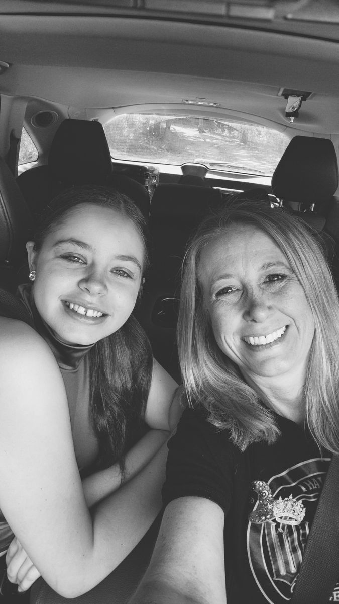 Black and white photo showing two people smiling together while seated in a car.