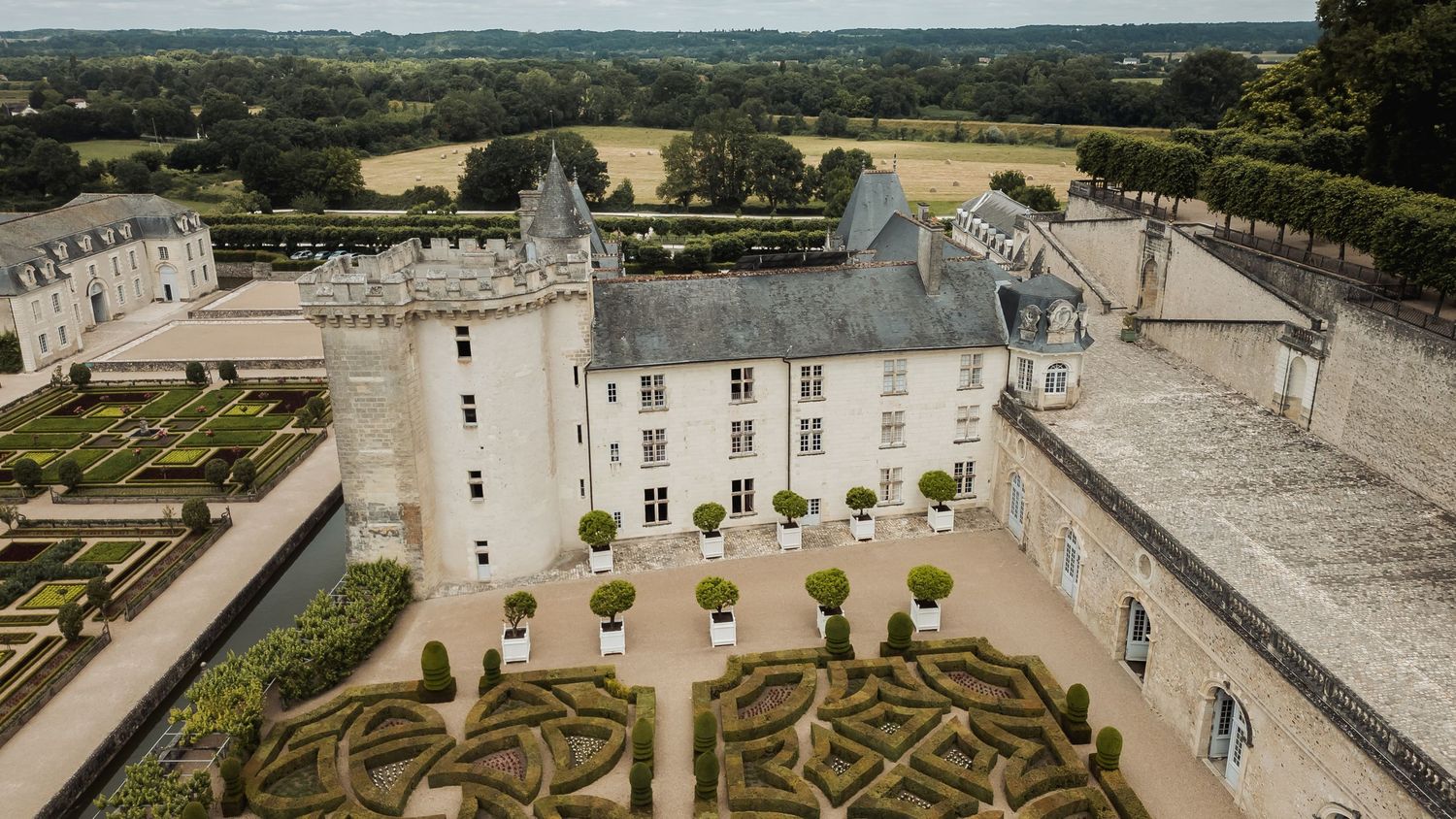 Aerial view of Villandry Chateau in France showing elegant geometric gardens and white stone architecture with towers.