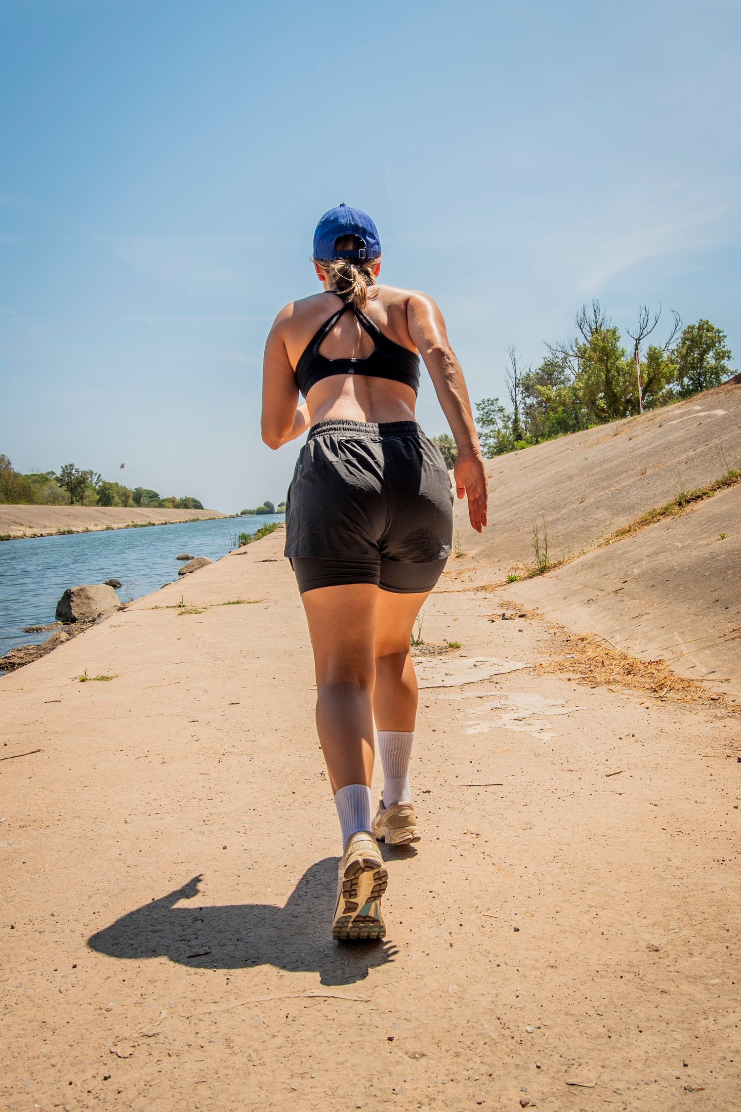 Athletic person running on a sandy incline near a beach, photographed in a sequential series of shots showing forward motion.