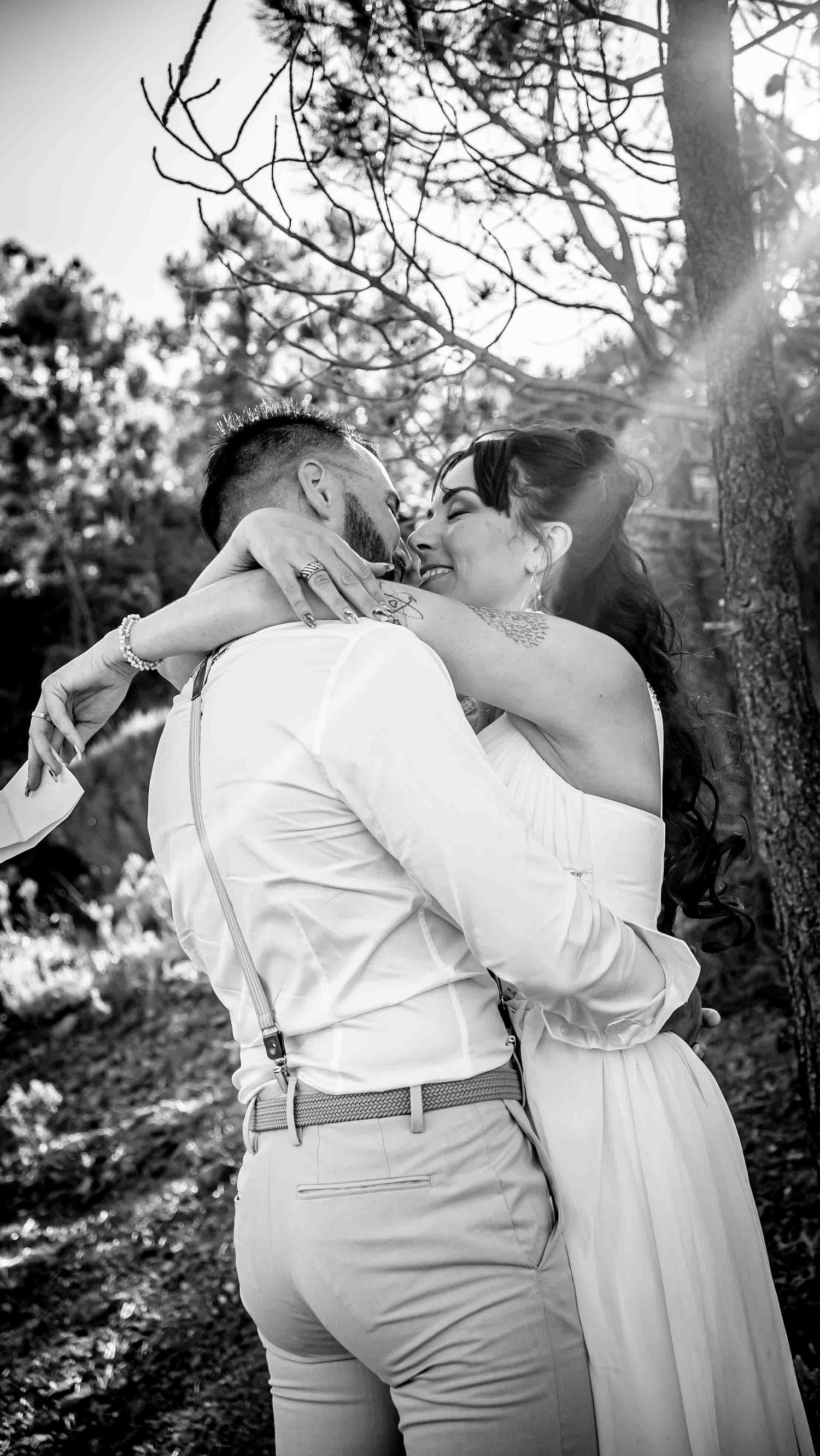 A couple shares an intimate moment while embracing in a black and white photo series taken outdoors.