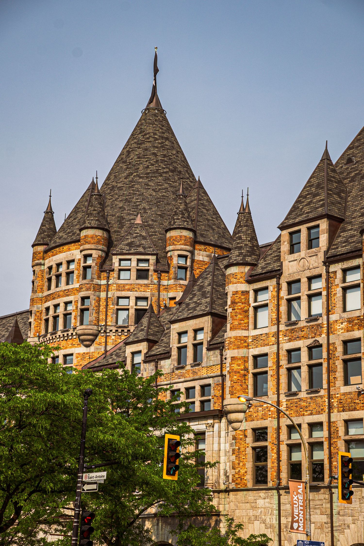 Gothic-style brick building with pointed spires and ornate stone architecture glowing in warm sunlight against blue sky.