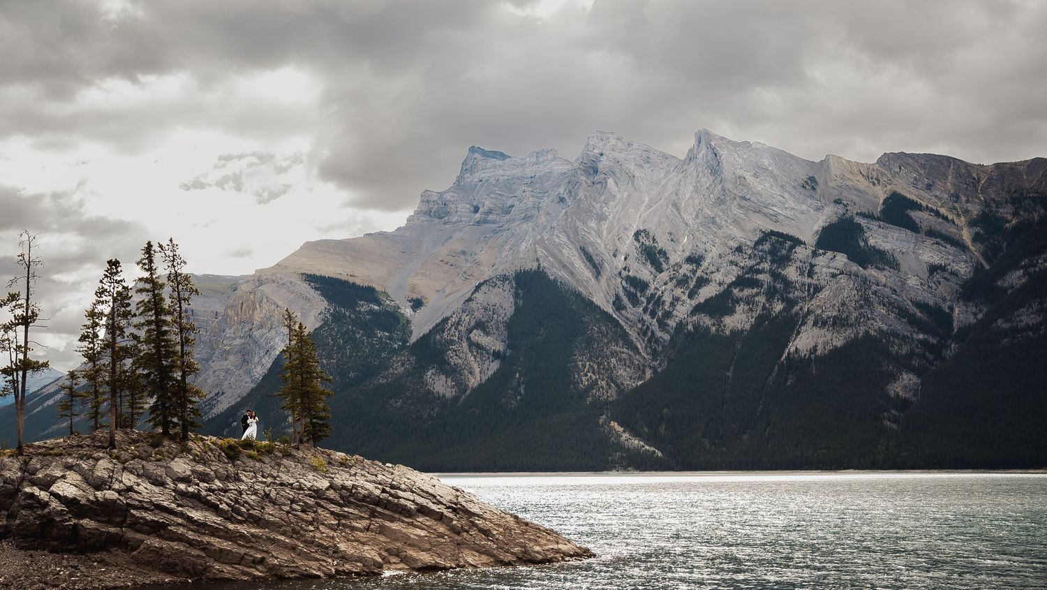 Dramatic mountain landscape with Lake Minnewanka and Mount Girouard in Banff National Park on a cloudy day.