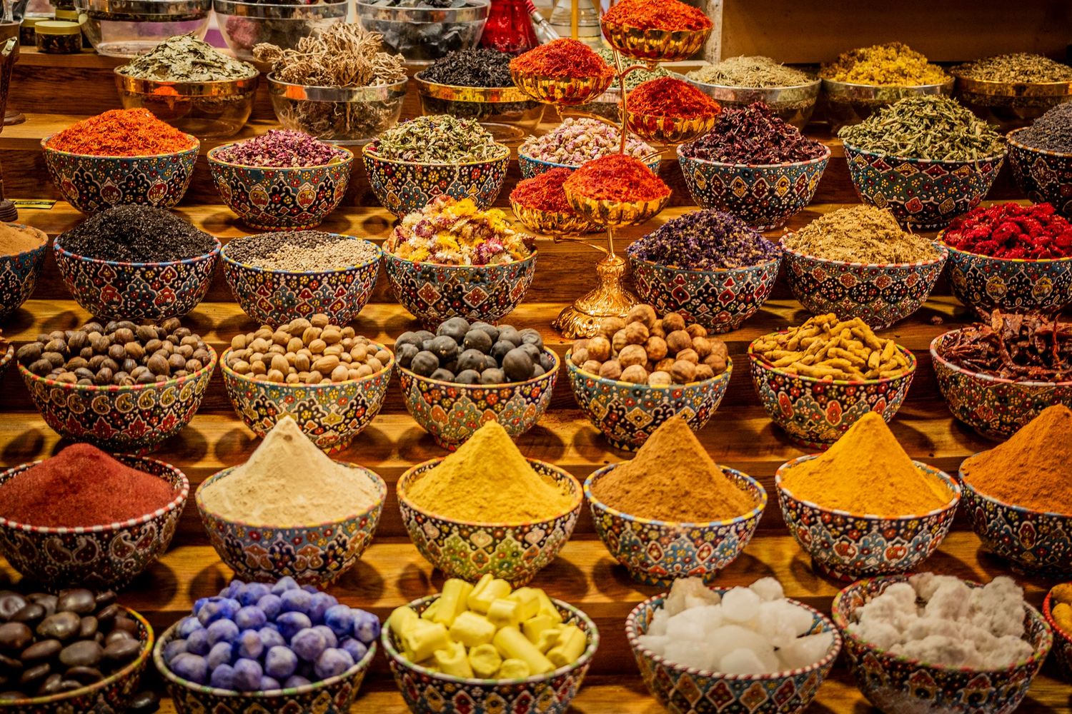 Colorful array of spices and dried ingredients in wooden bowls at a traditional Eastern market spice bazaar.
