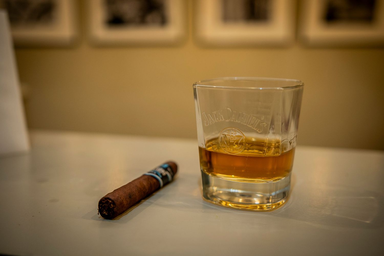 A glass of whiskey on a table next to an unlit brown cigar creates a classic relaxation scene.