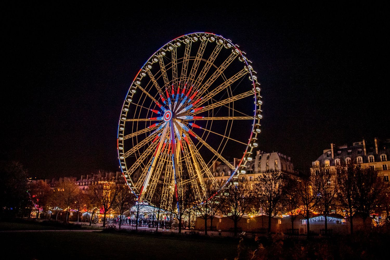 Illuminated ferris wheel glows against dark night sky with warm festive lights at winter fair.