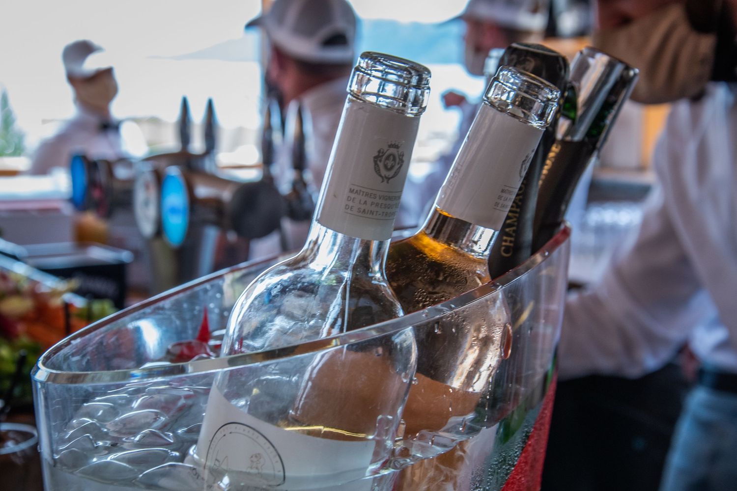 Close-up view of liquor bottles with ice in a glass during drink service at a bar and restaurant setting.