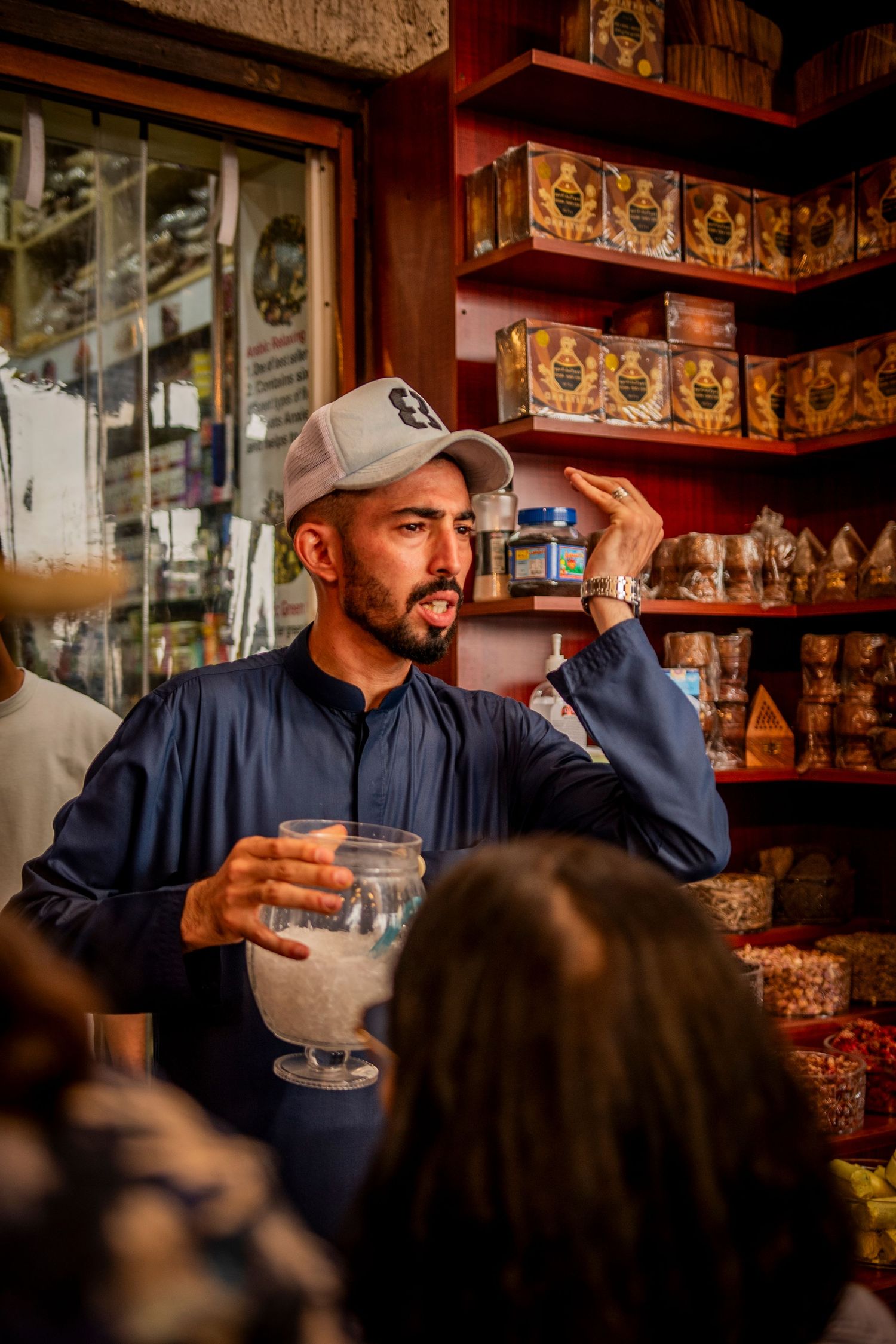 A person drinking in an atmospheric bar with shelves of bottles visible in the background.