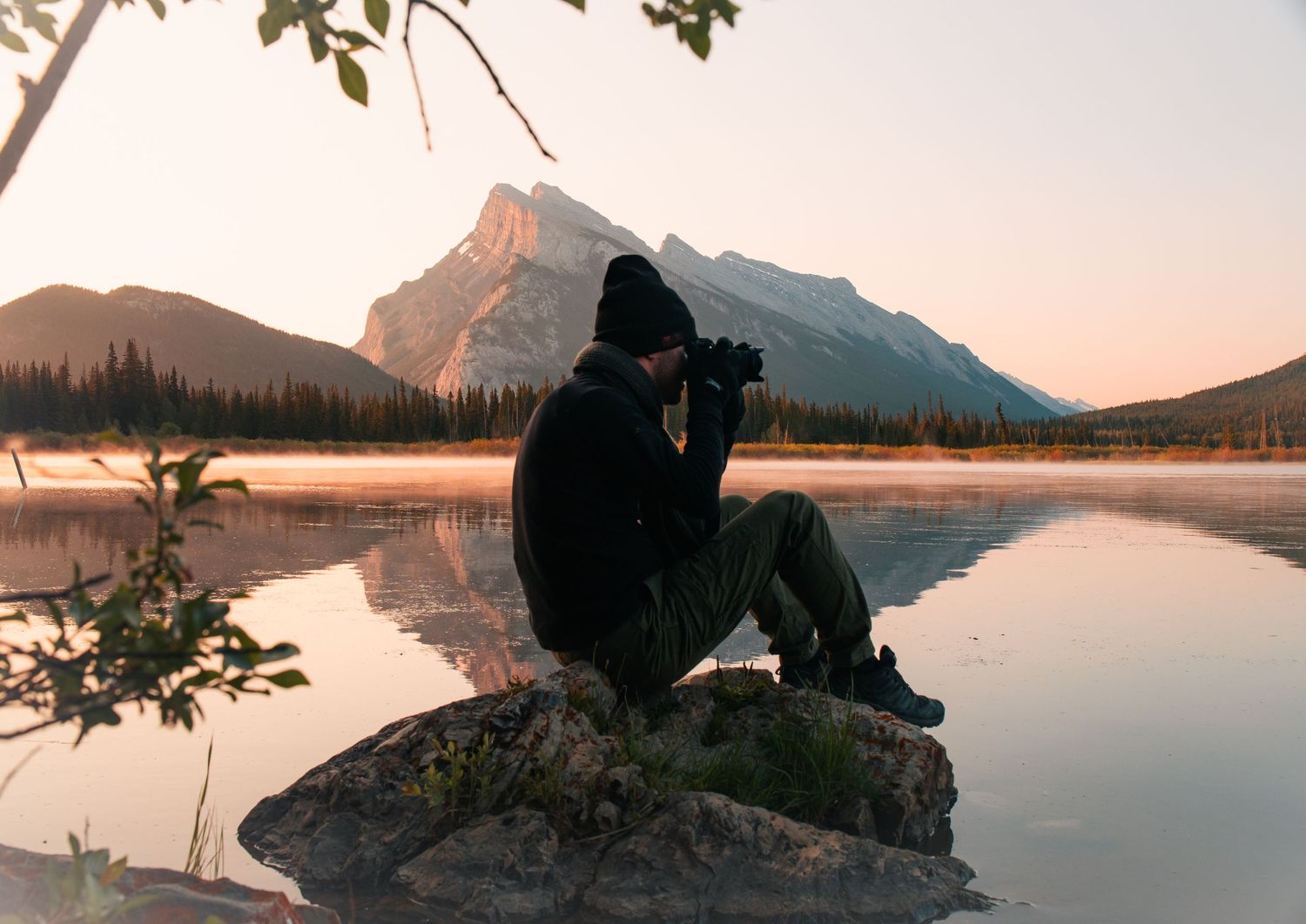 Scenic panorama of silhouetted figures watching sunset over tranquil mountain lakes and rugged peaks.