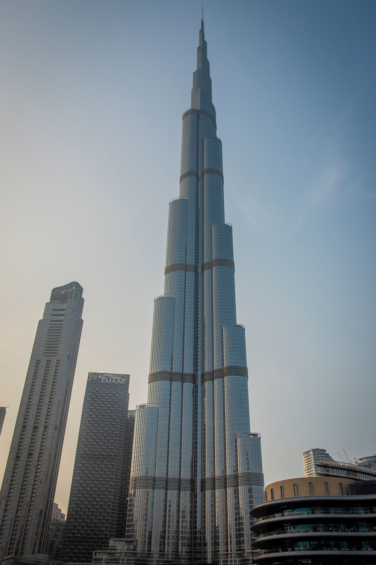 Architectural progression sequence of Burj Khalifa skyscraper rising against hazy Dubai sky shows its towering dominance.
