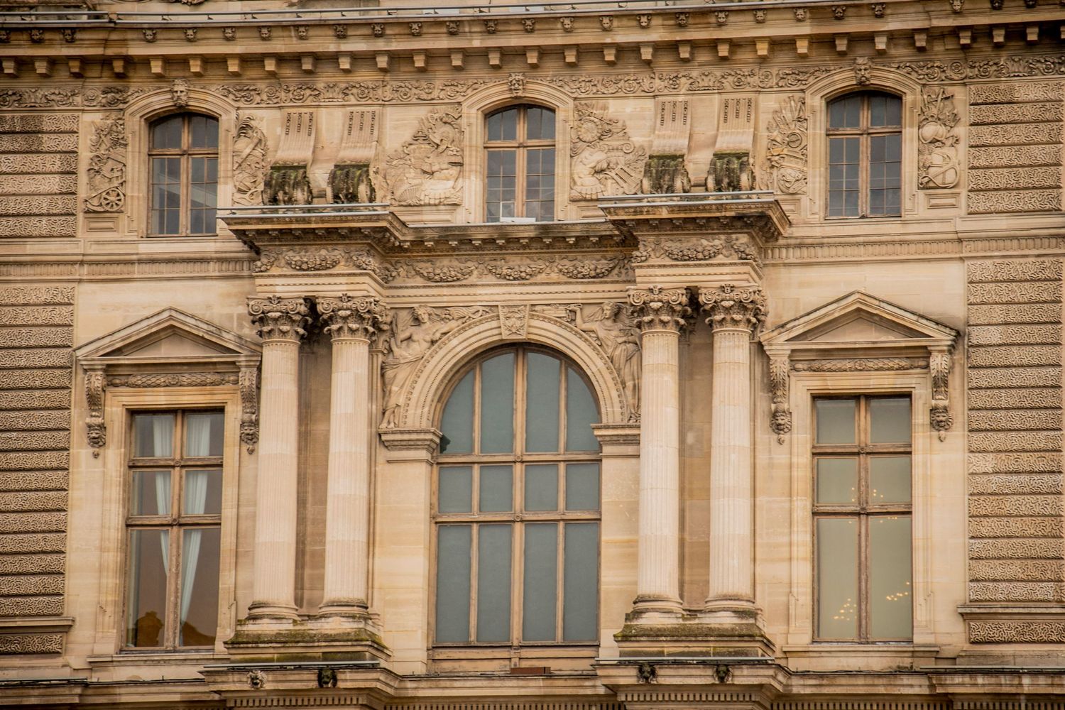 Ornate classical architectural detail with tall windows and carved stone decorative elements on a historic building facade.