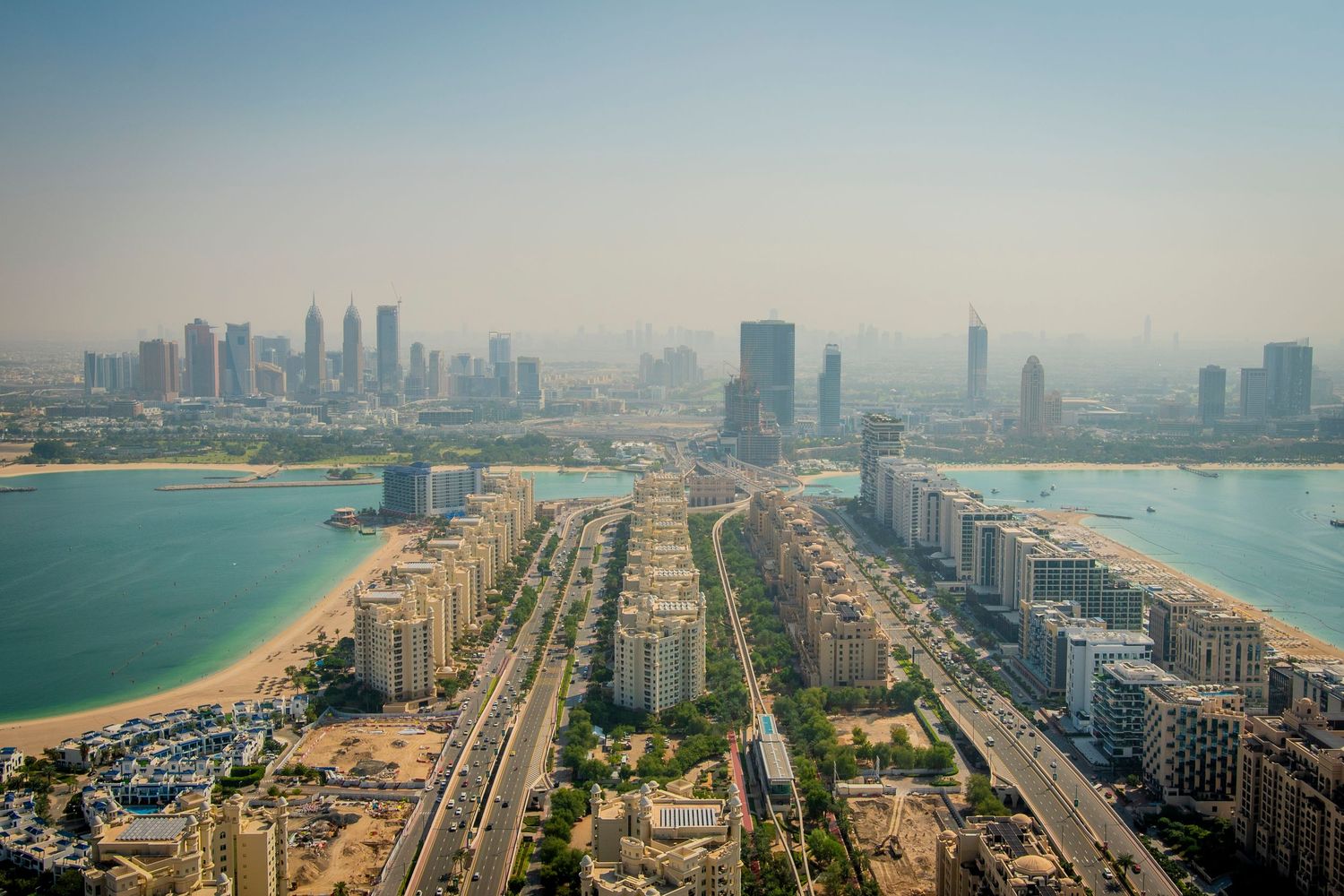 Aerial panoramic cityscape view of Abu Dhabi's modern skyscrapers, beaches, and waterfront along the Persian Gulf coast.