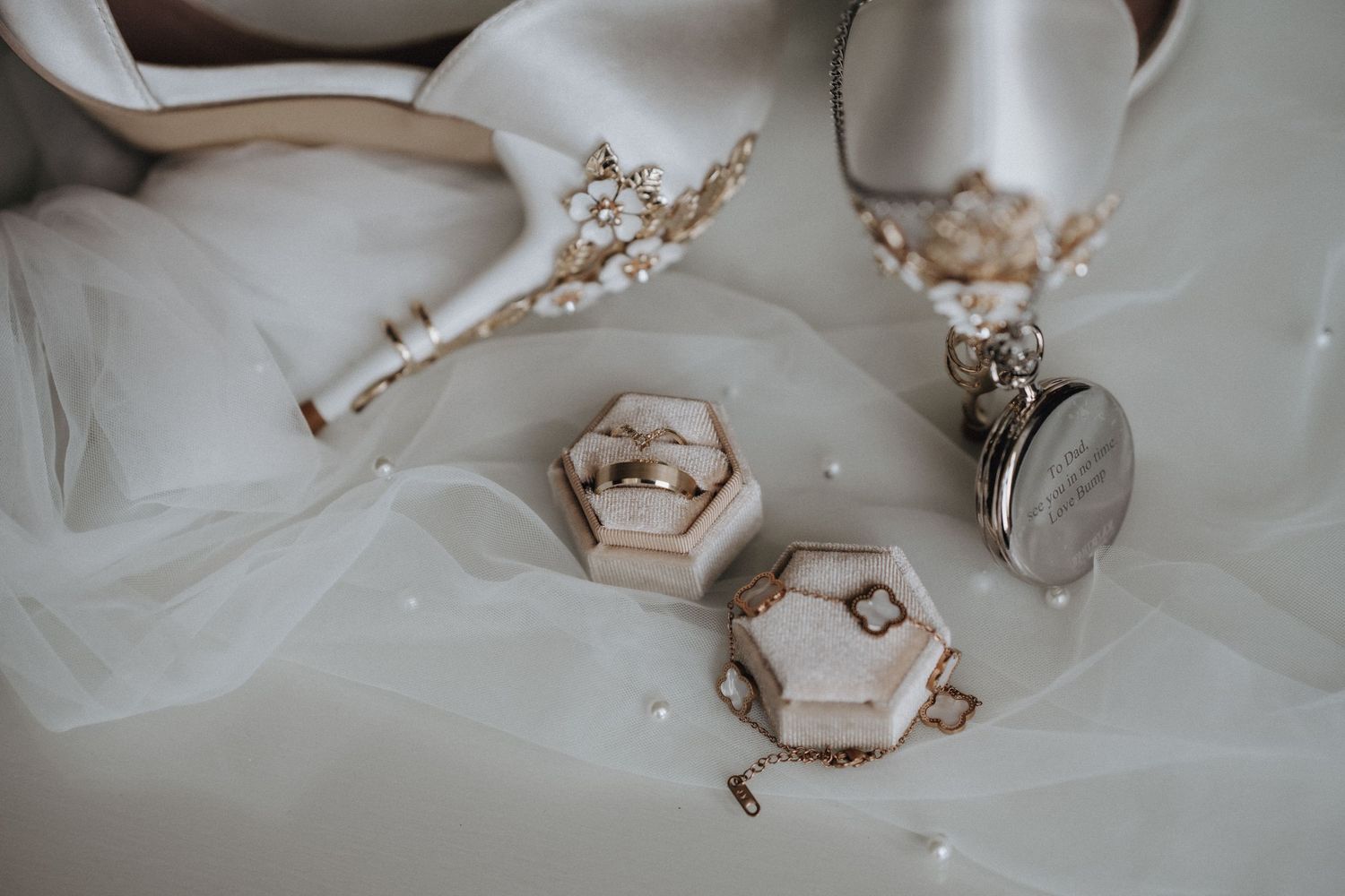 Elegant wedding details with hexagonal ring boxes and bridal accessories on white tulle fabric.