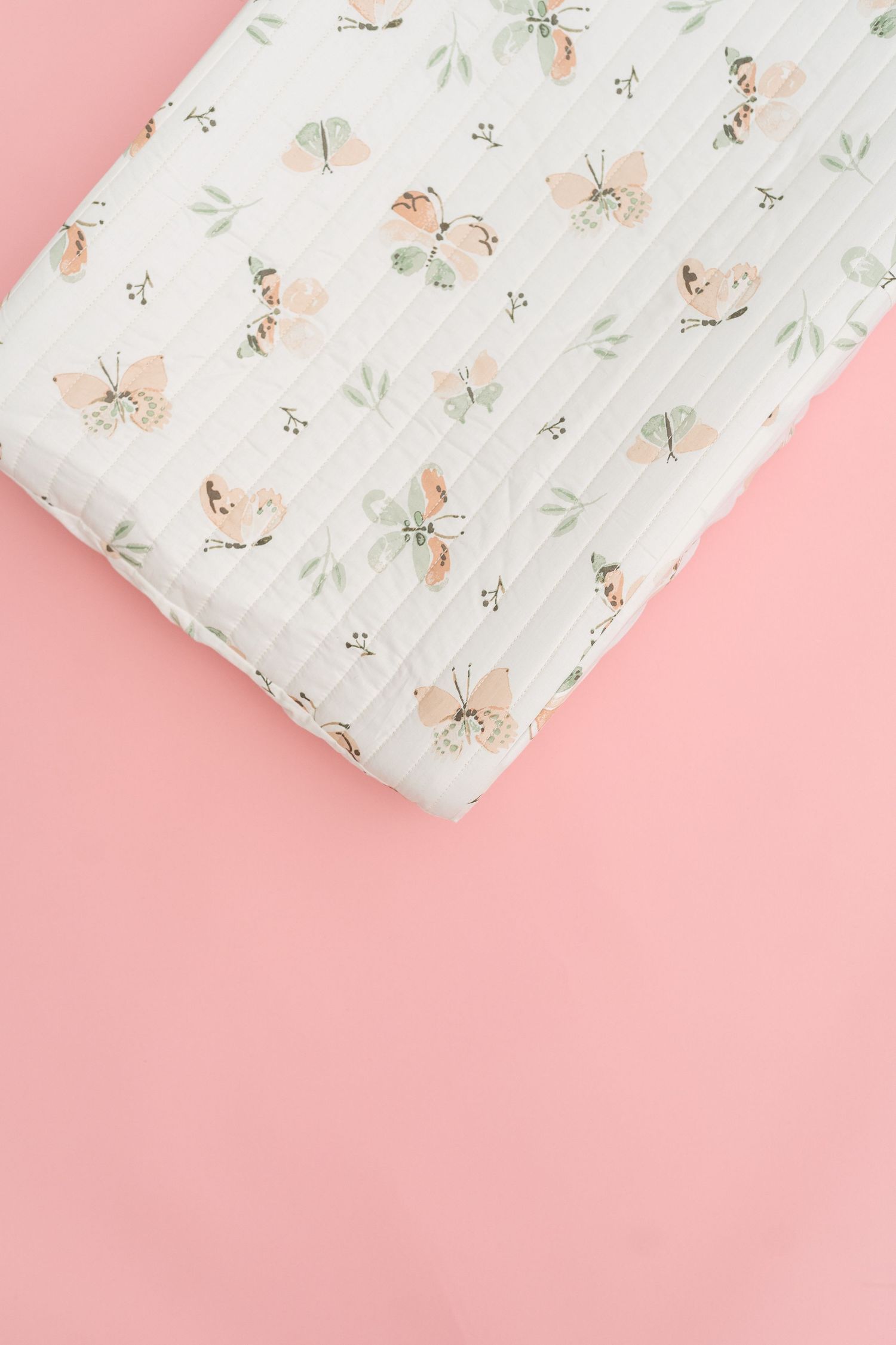 White floral patterned baby blanket displayed on pink background.