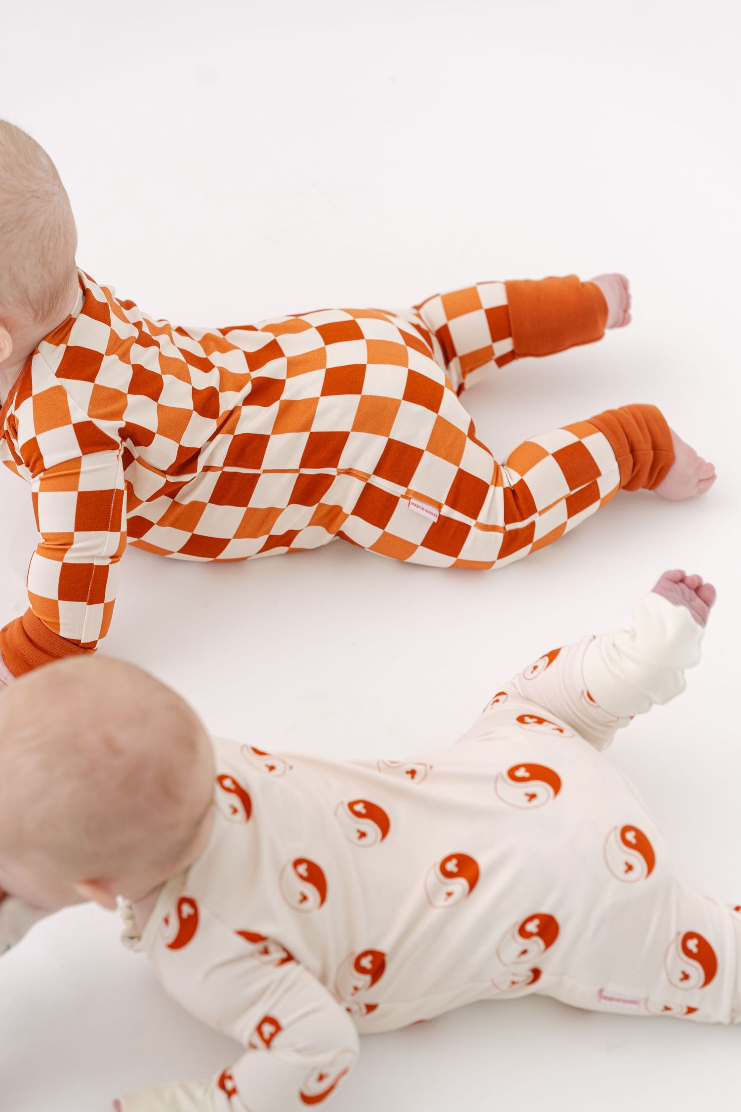 Orange and white checkered onesies laid out on a white surface.