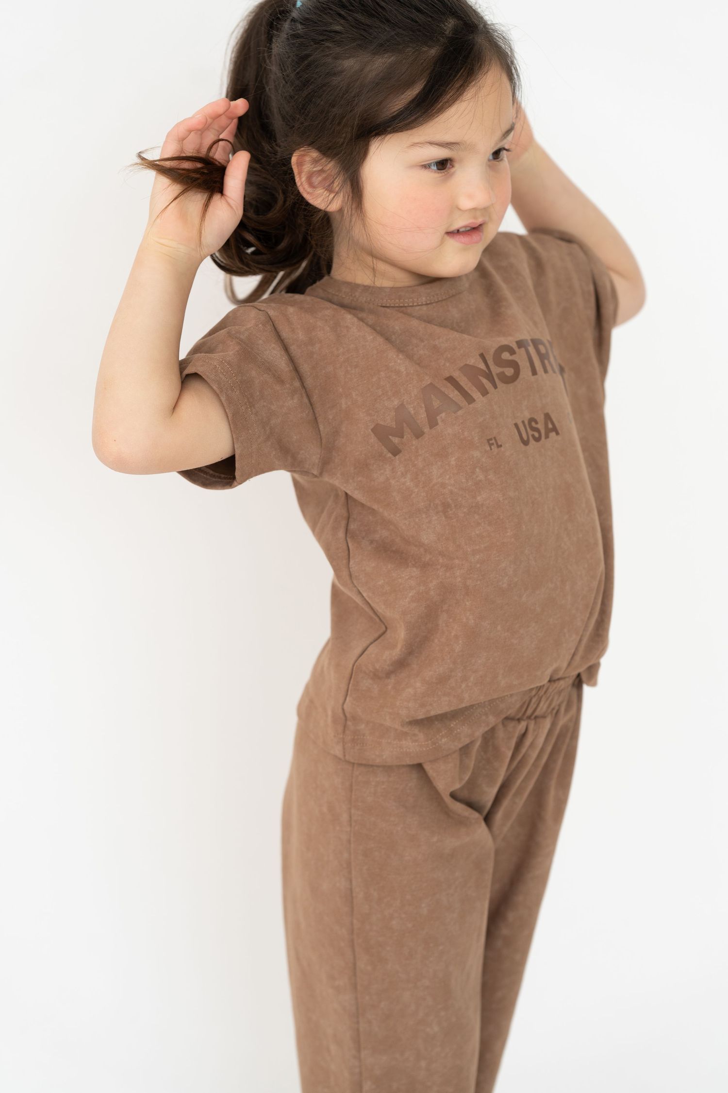 Child wearing a brown casual cotton outfit against white background.
