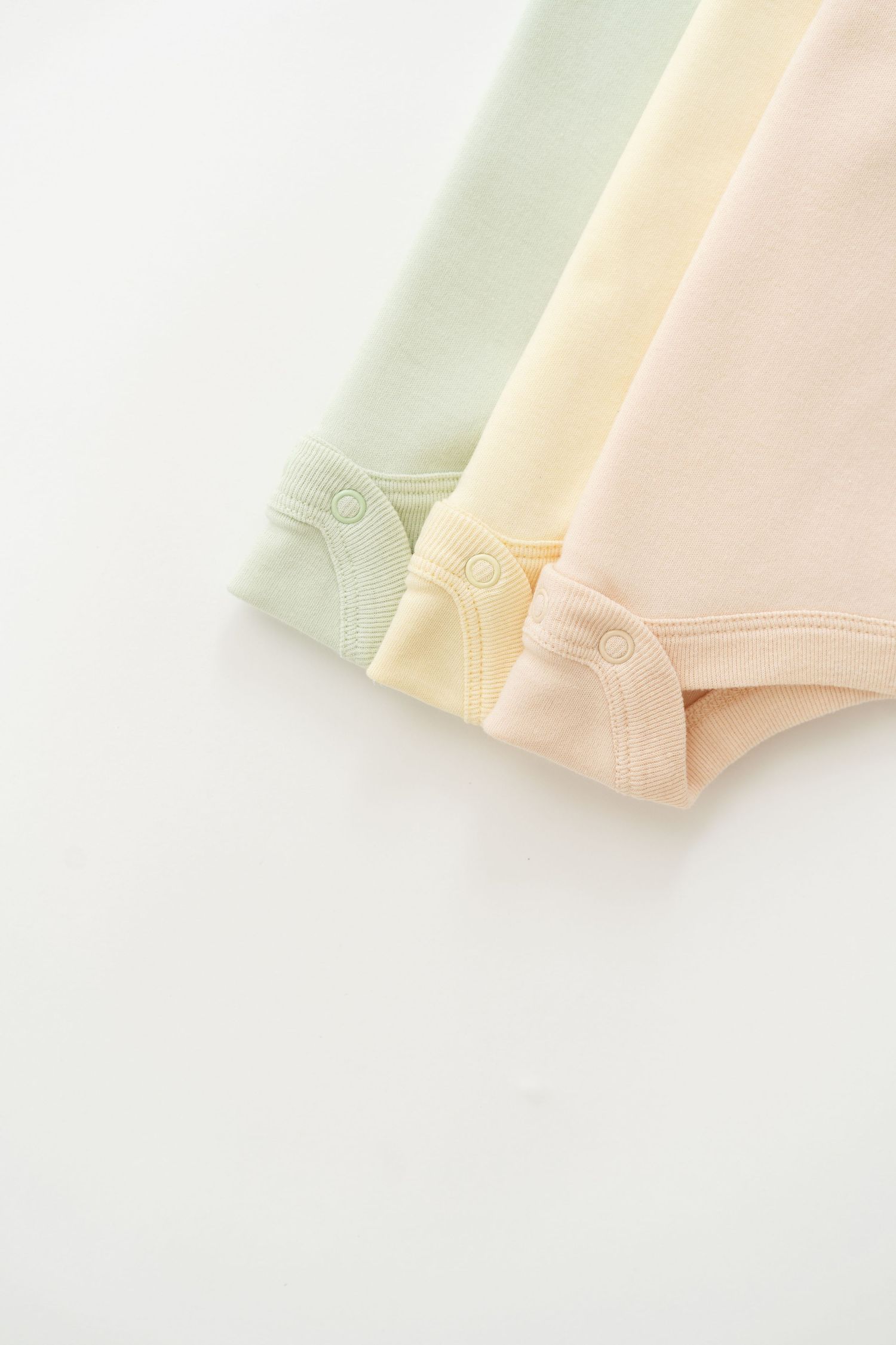 Three soft pastel-colored fabric swatches in mint green, yellow, and peach tones.