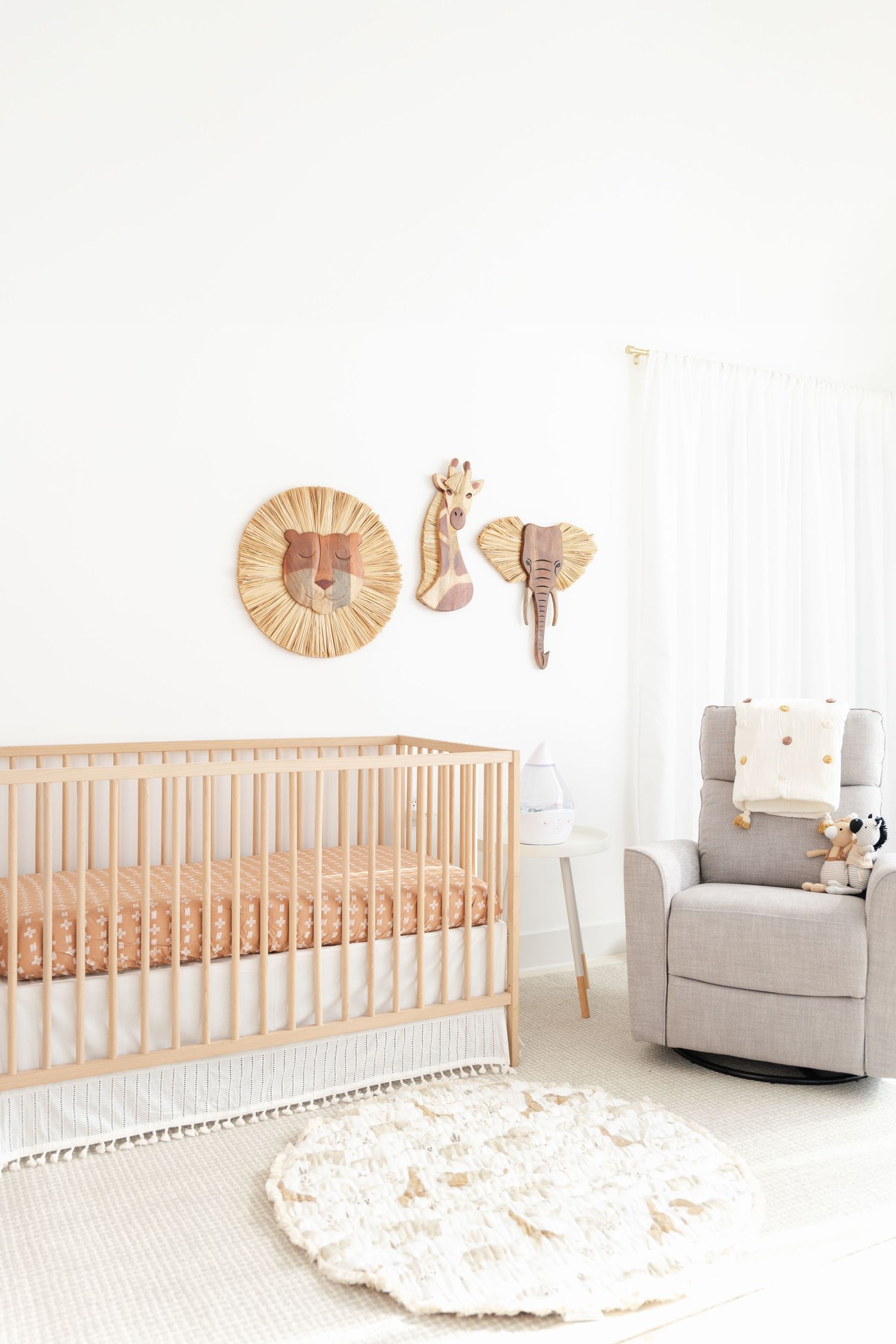 Minimalist nursery with wooden crib, gray rocking chair, and decorative wall art.