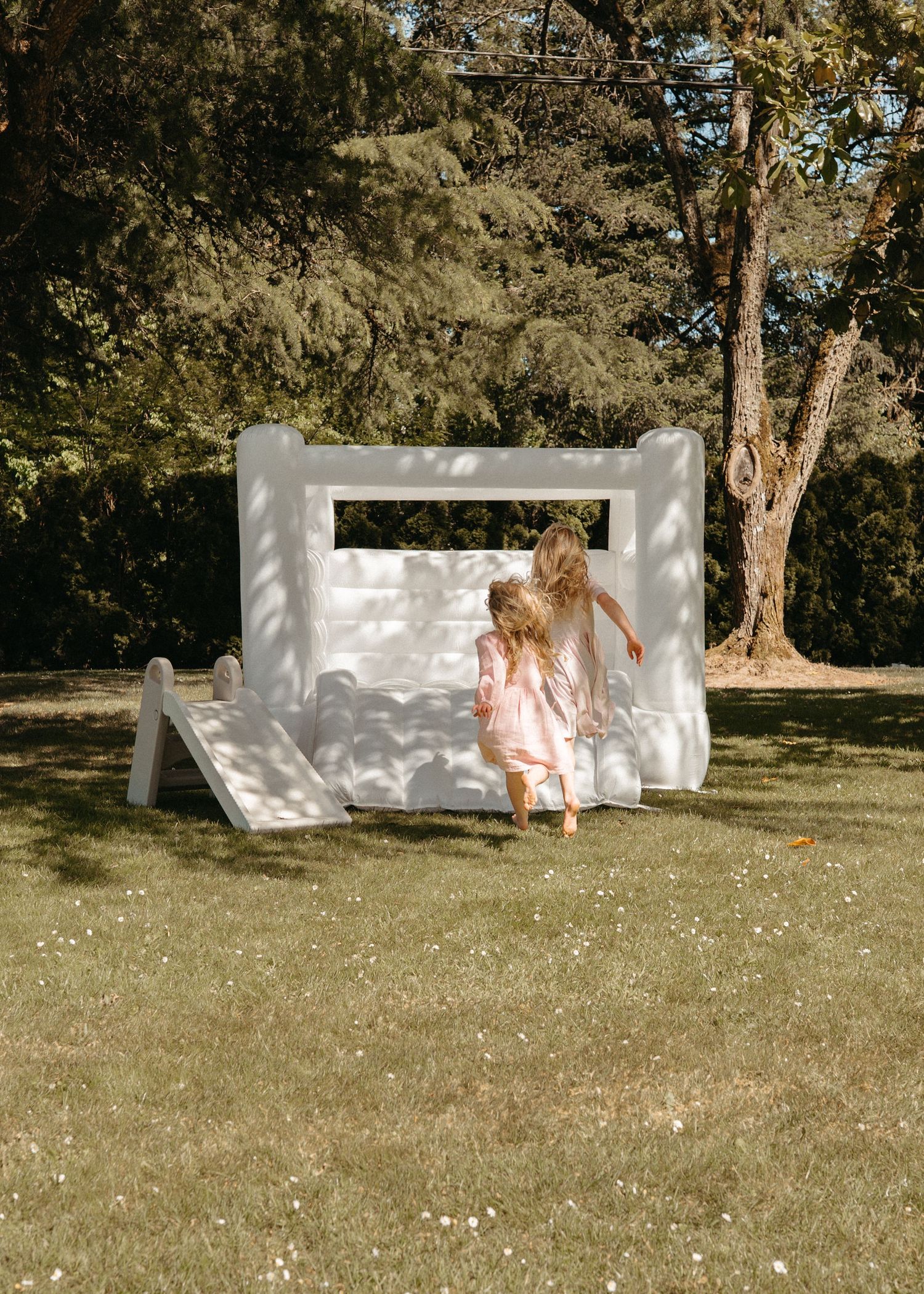A whimsical white box-like structure in a garden setting with wildflowers scattered across a green lawn.