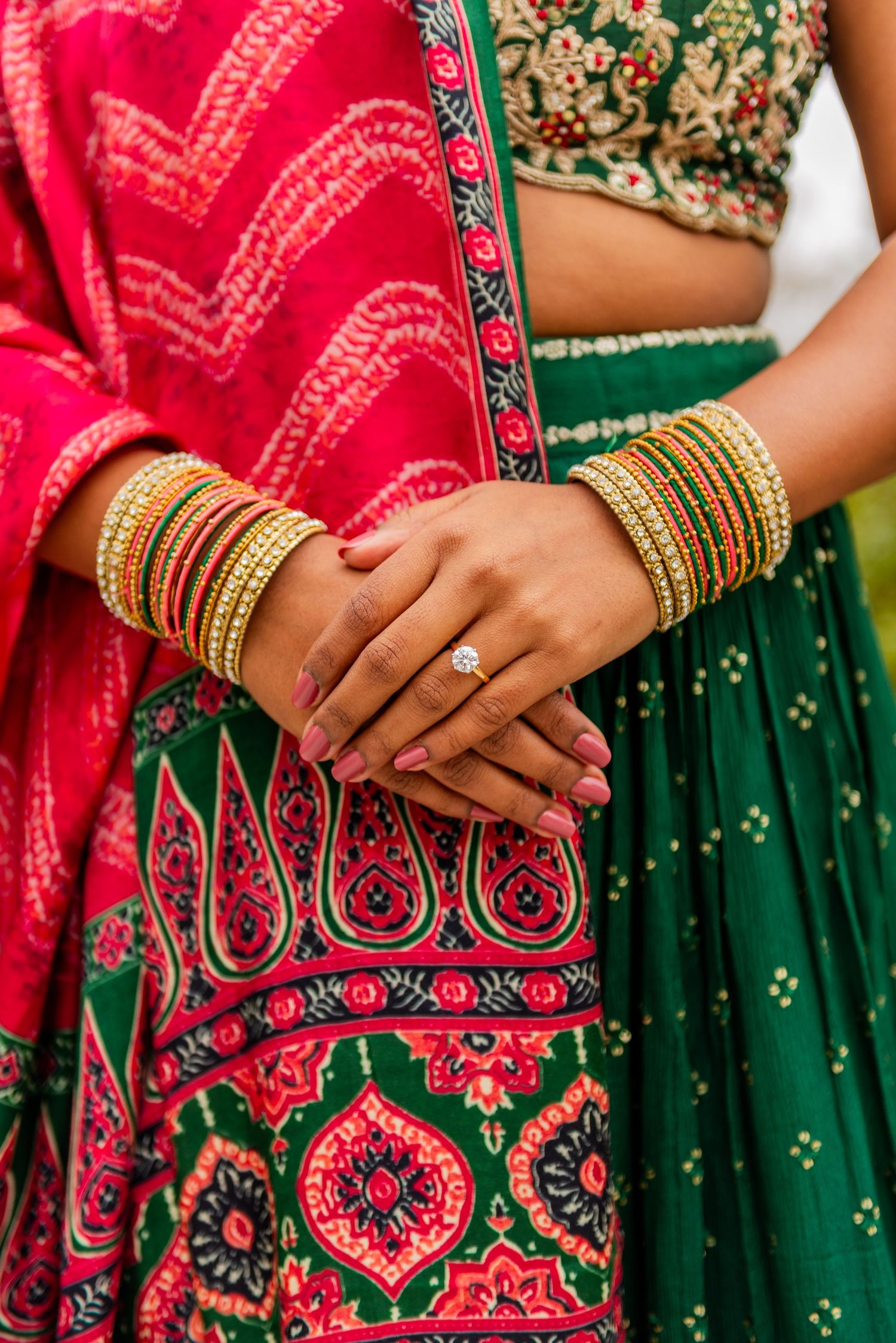 Close up of hands adorned with gold bangles wearing traditional Indian bridal attire.