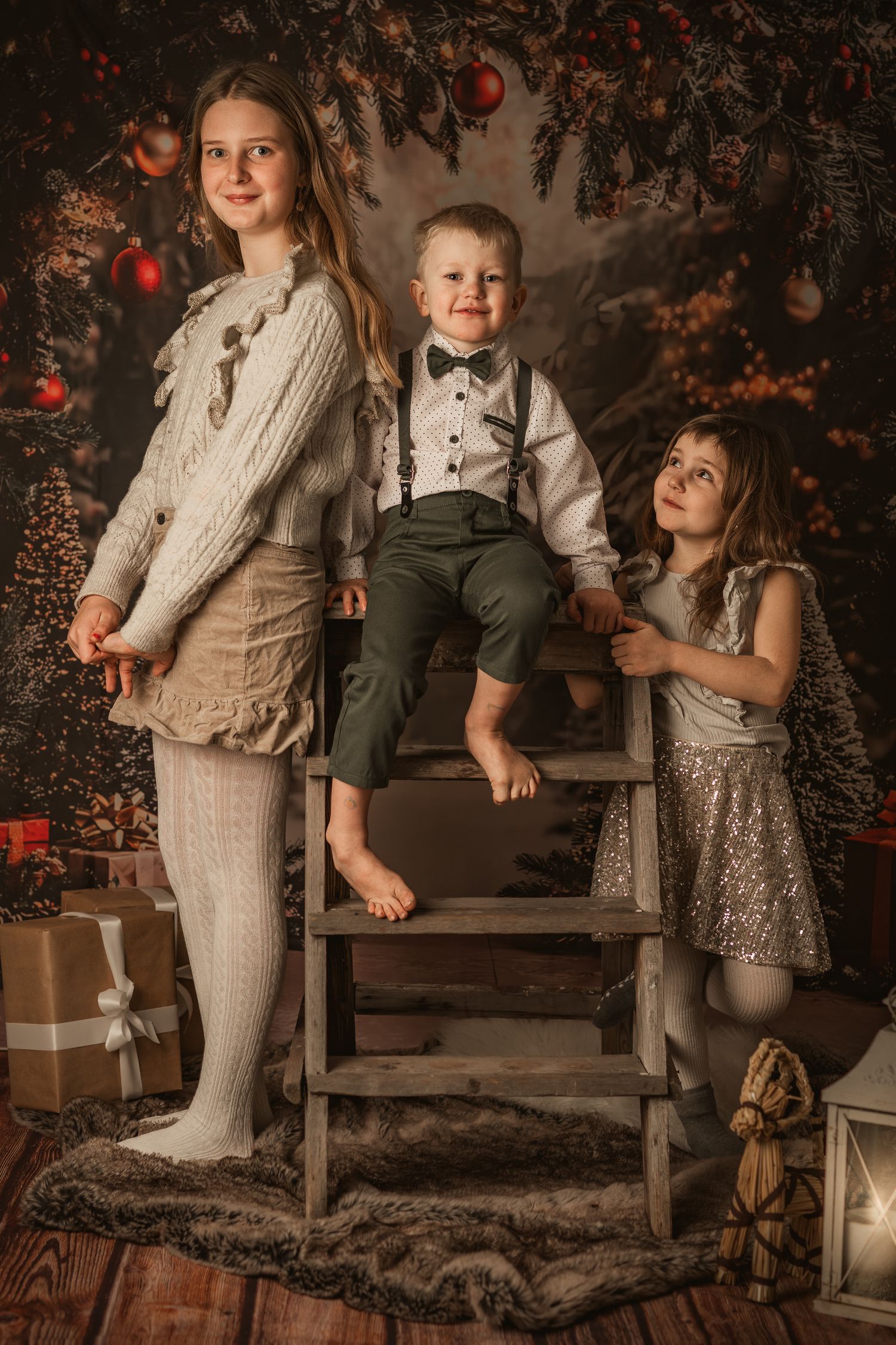 Vintage-style holiday portrait featuring three siblings on rustic wooden stairs with festive decorations and gifts.