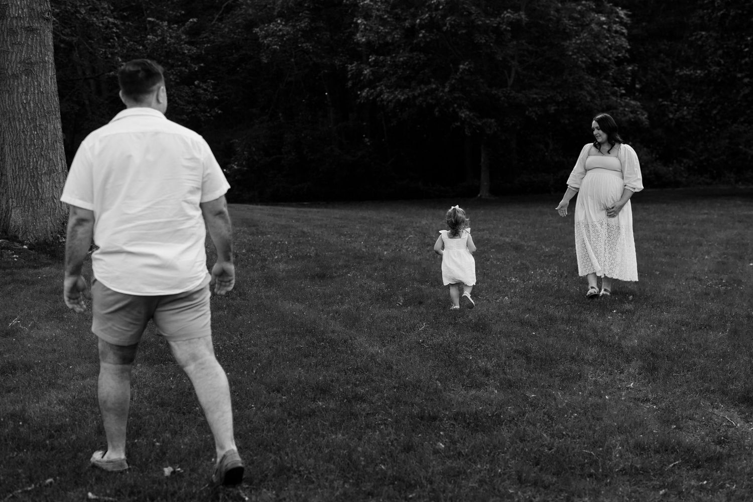 A family enjoying a playful moment together on a grassy field in black and white.